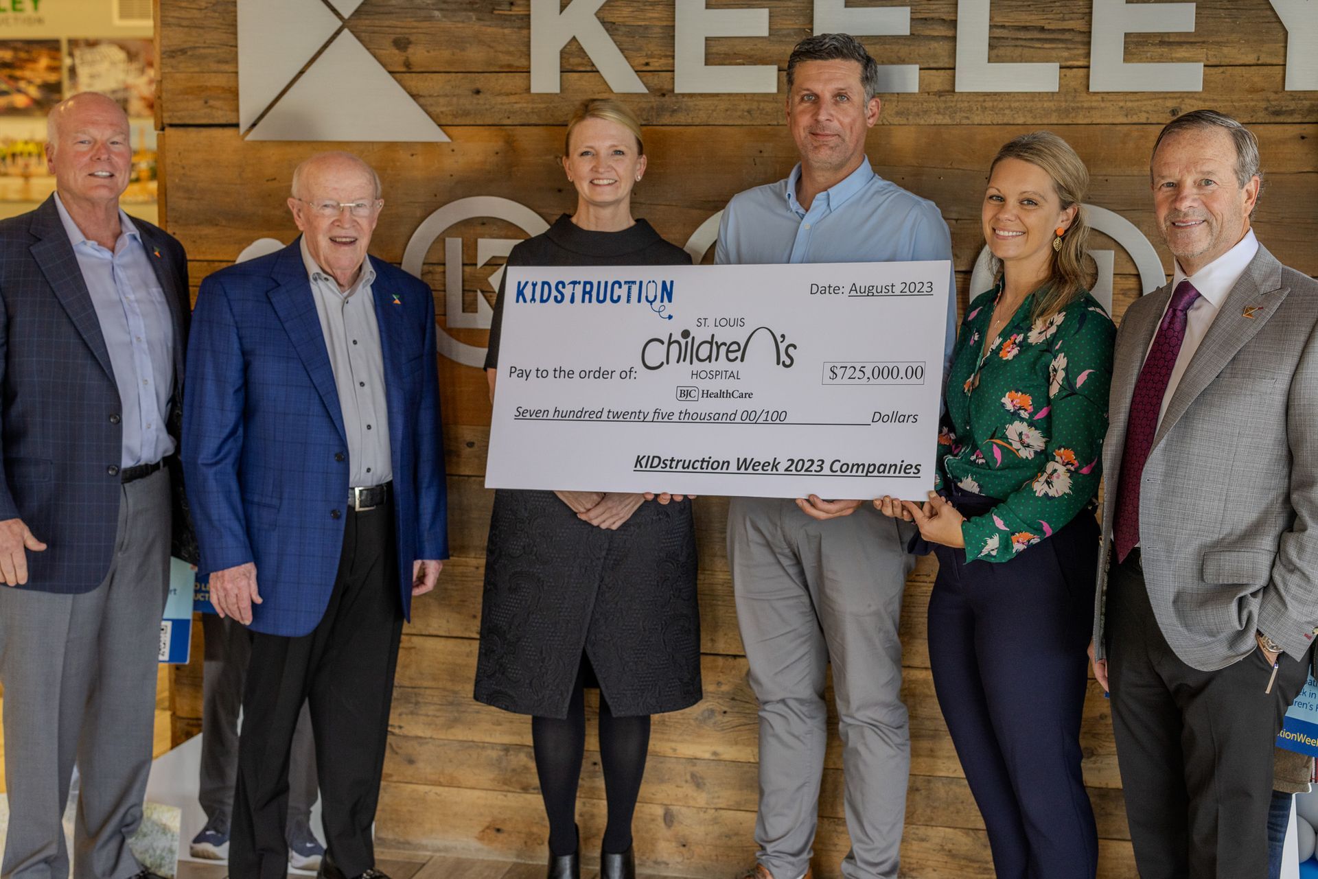 A group of people standing next to each other holding a large check.