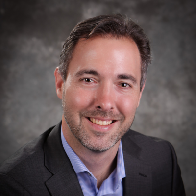 A man in a suit and blue shirt is smiling for the camera.