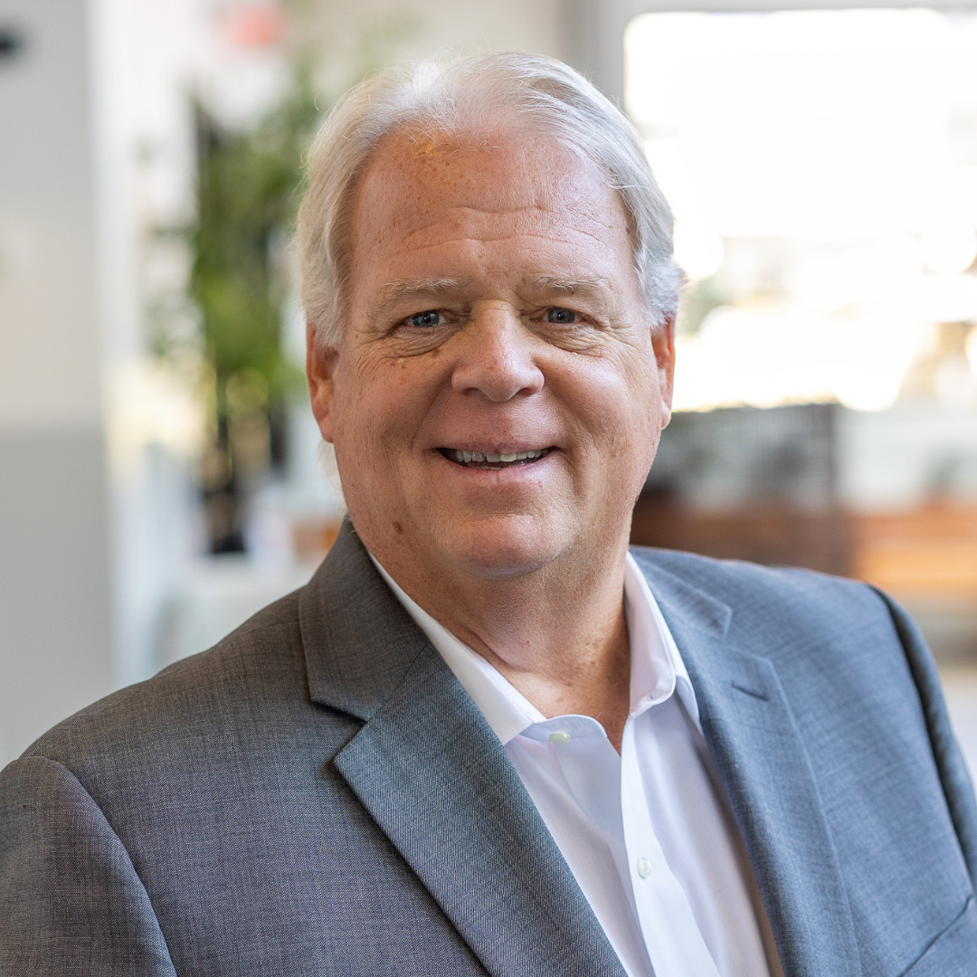 A man in a suit and white shirt is smiling for the camera.