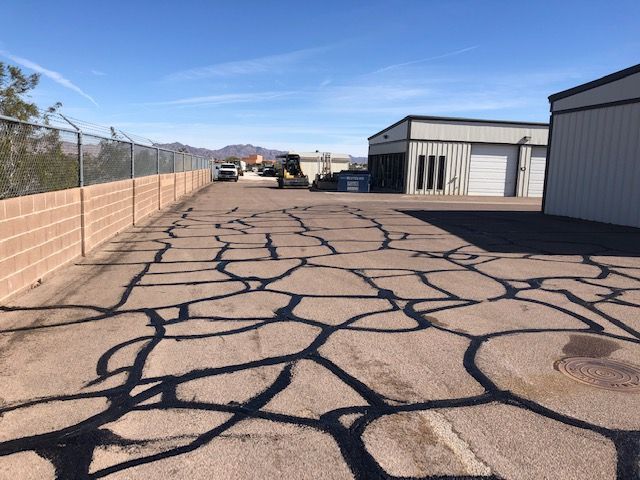 A driveway with a fence and a building in the background