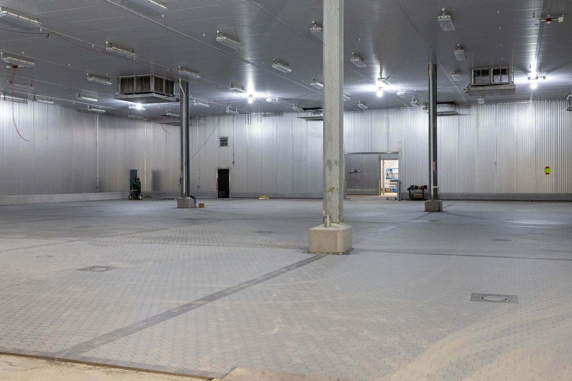 A large empty warehouse with a lot of lights on the ceiling.