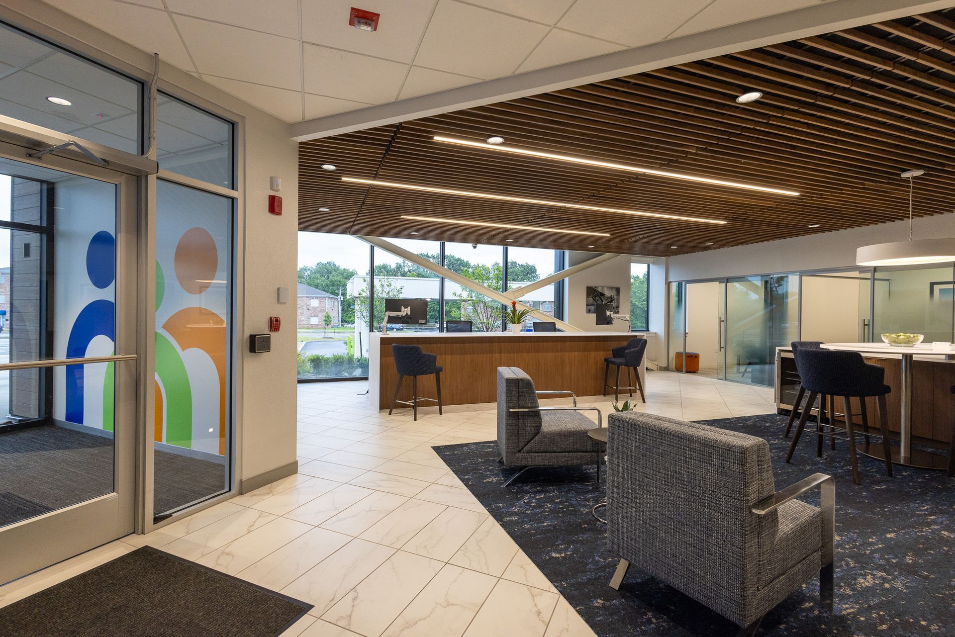 A lobby with chairs , tables and a counter in a building.