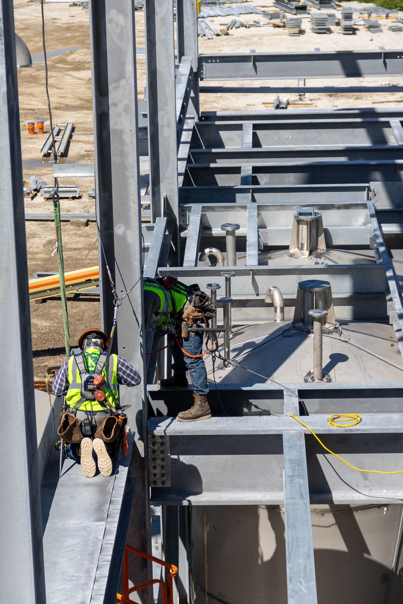 A construction worker is standing on top of a metal structure.