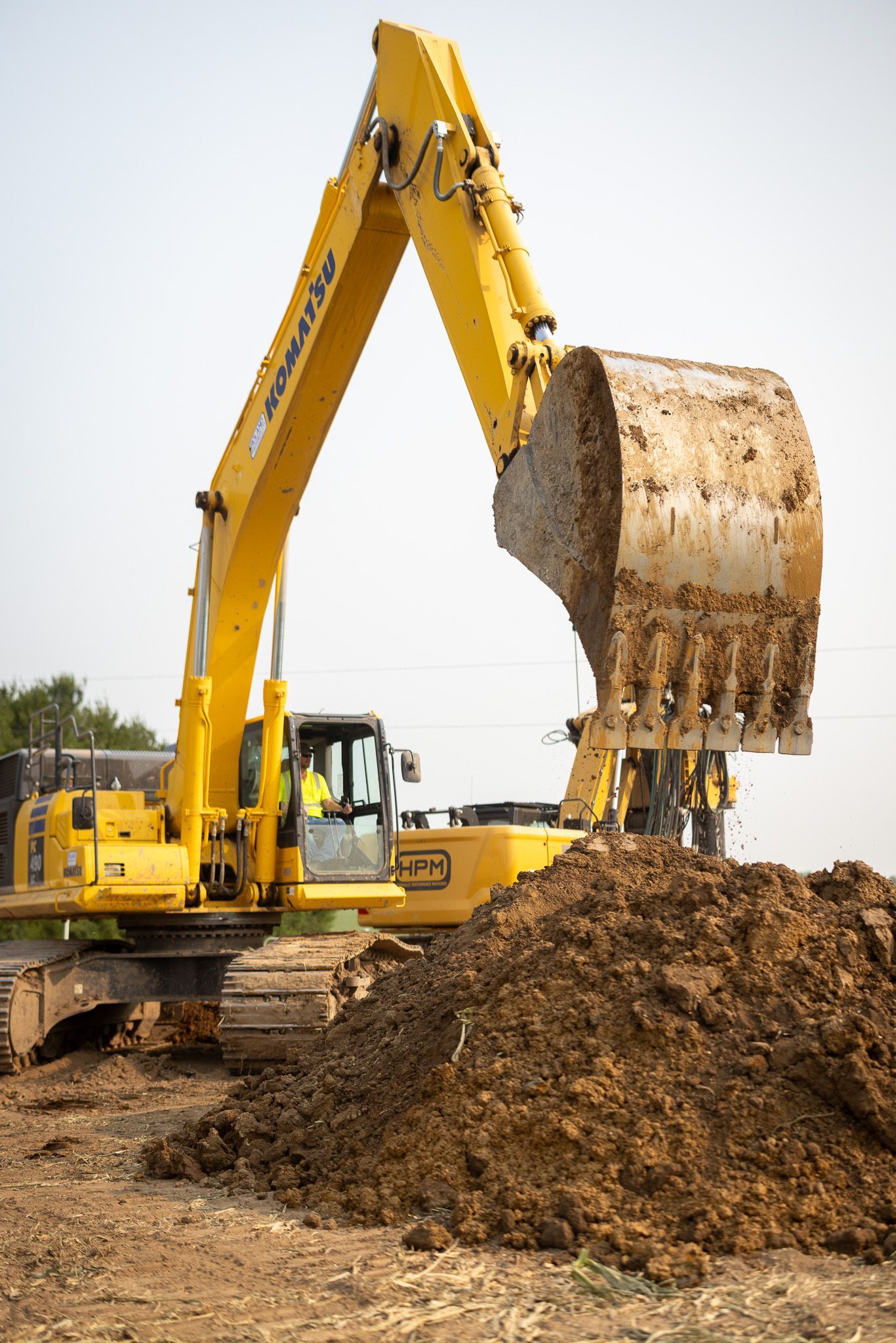 A yellow excavator is digging a pile of dirt on a construction site.