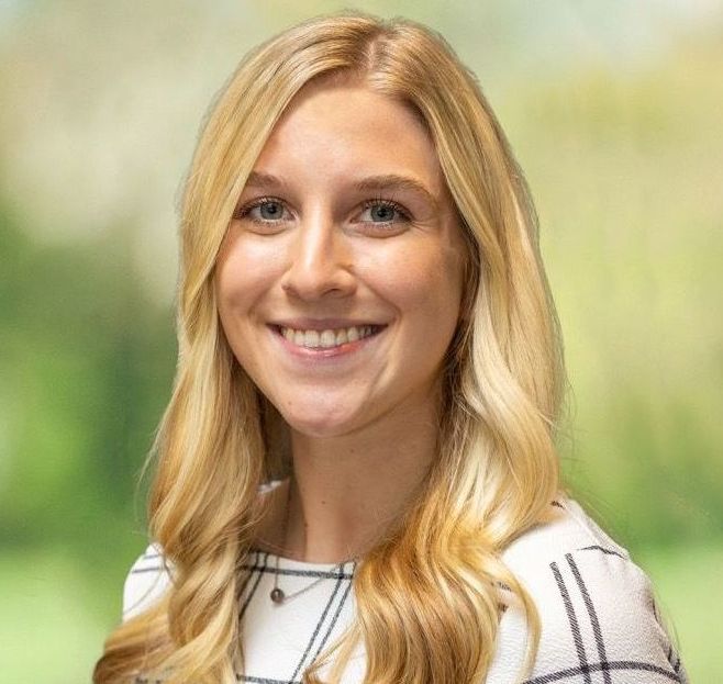 A woman with long blonde hair is smiling for the camera.