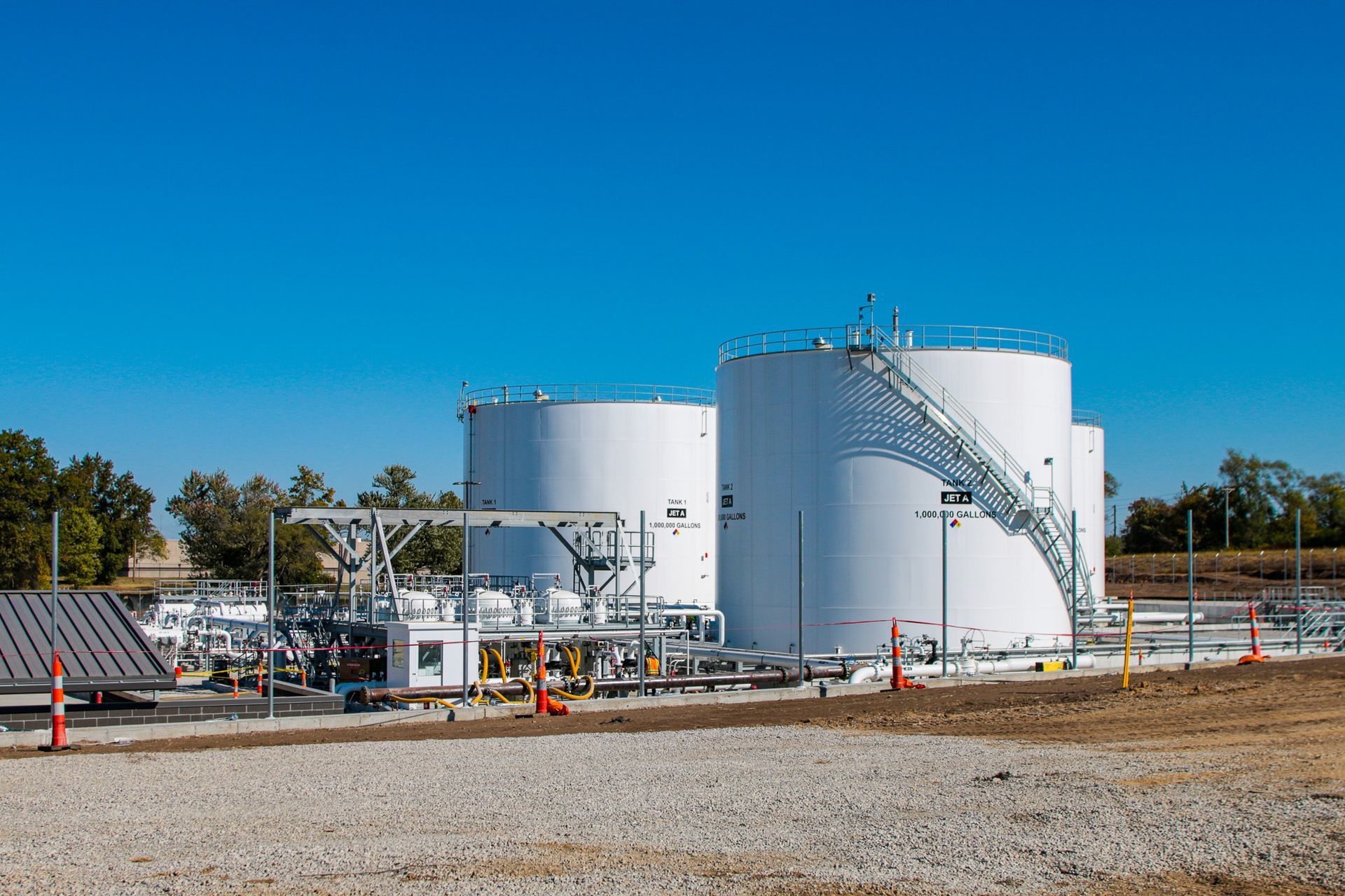 A group of large white tanks sitting on top of a gravel field.