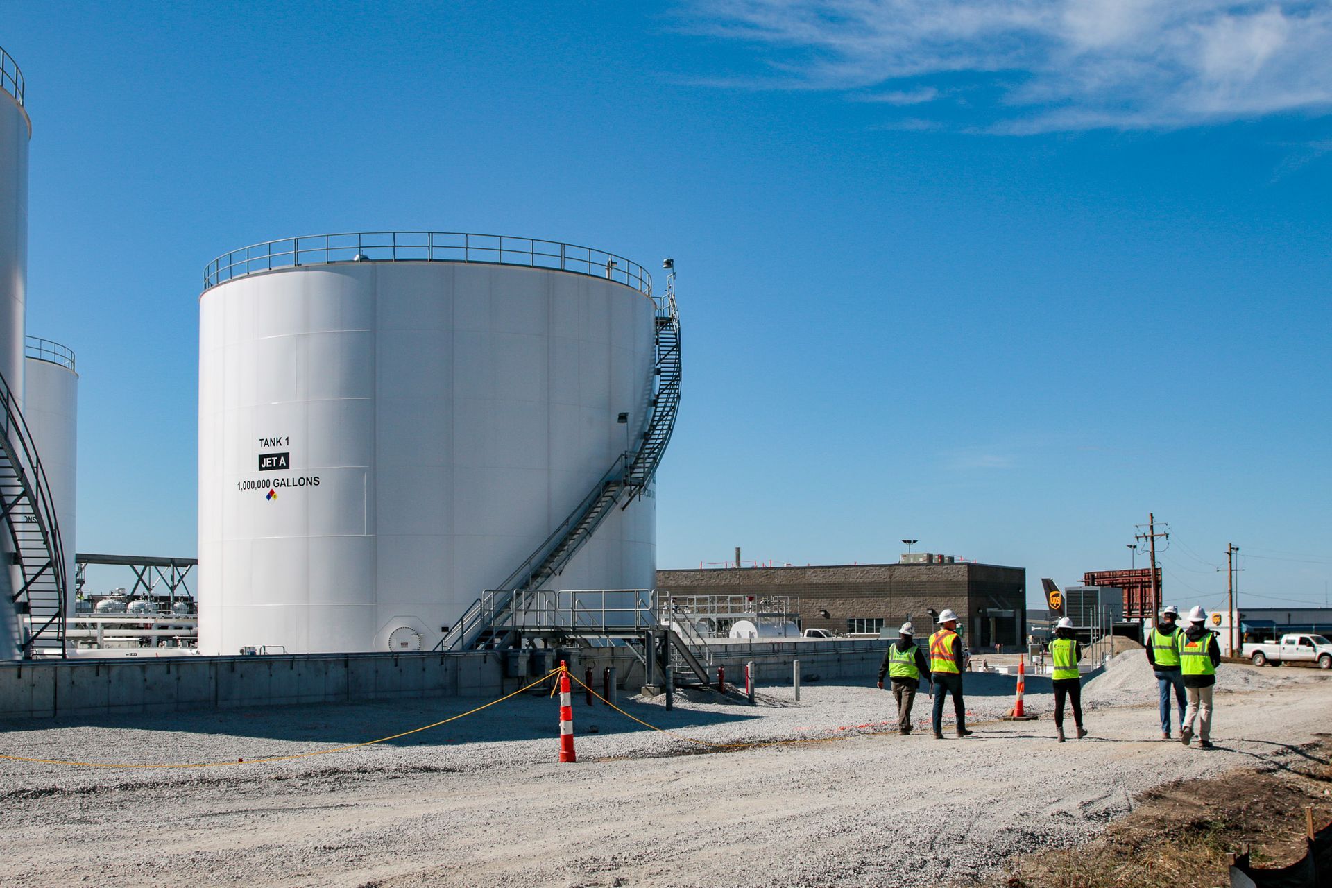 A group of people are standing in front of a large white tank.