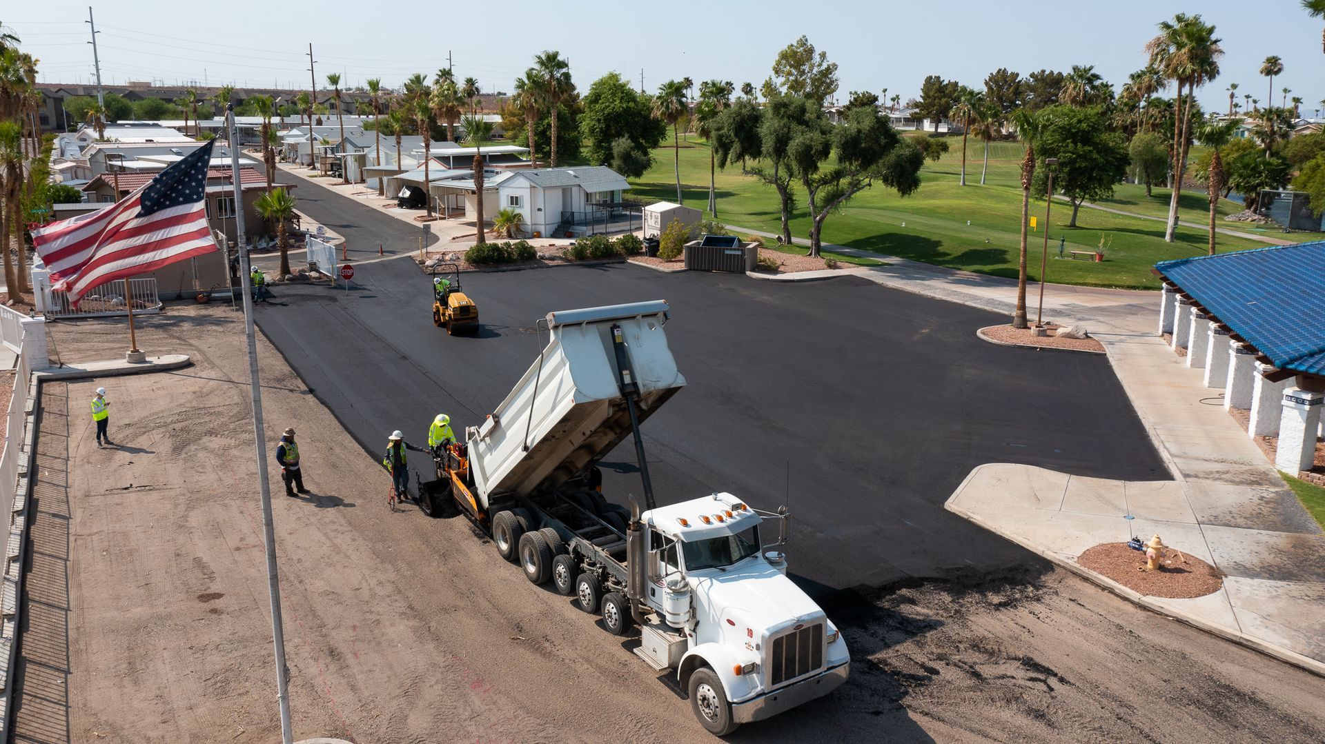 An aerial view of a dump truck being loaded with asphalt