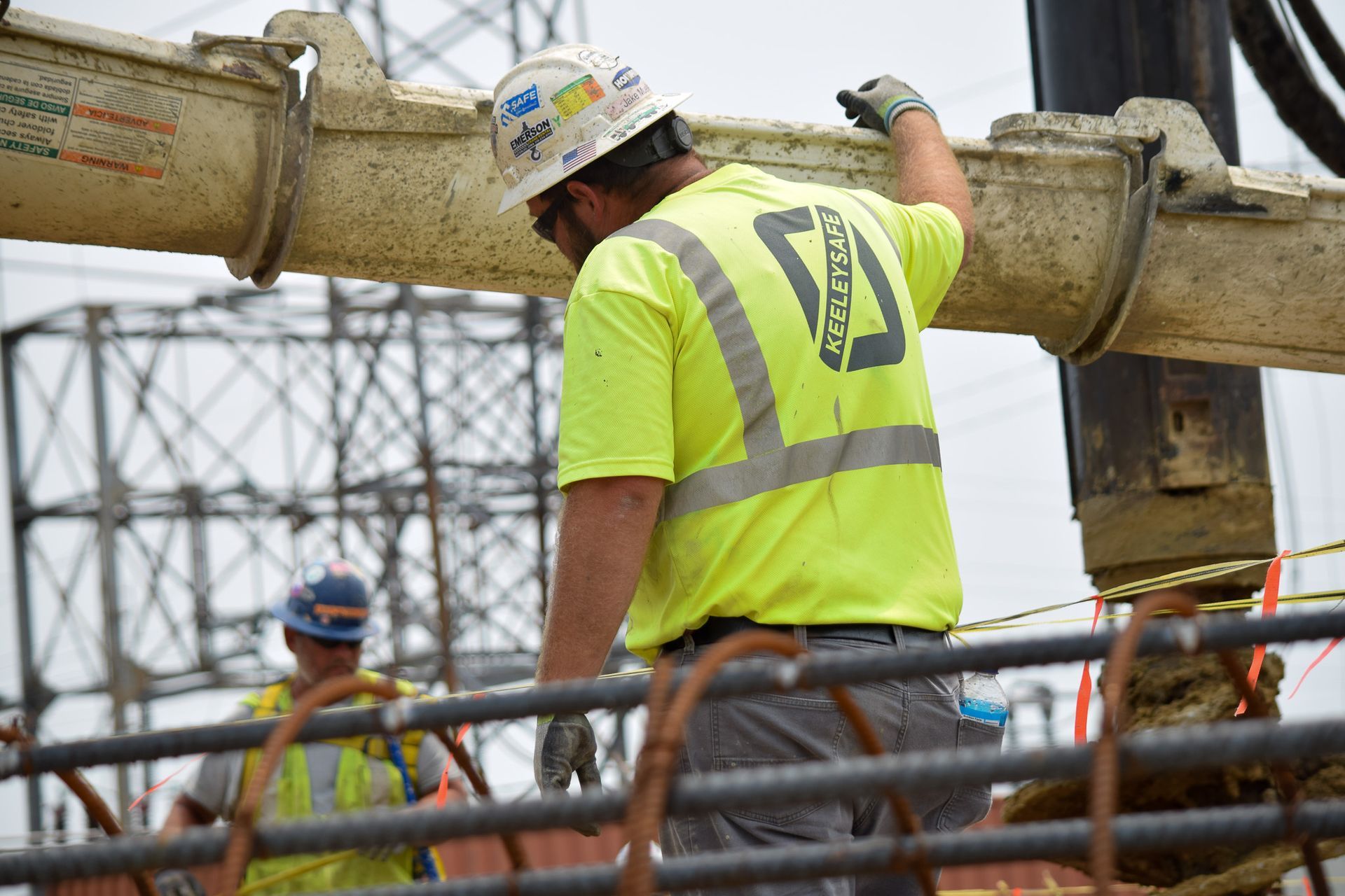 A construction worker wearing a yellow shirt and a hard hat is working on a pipe.