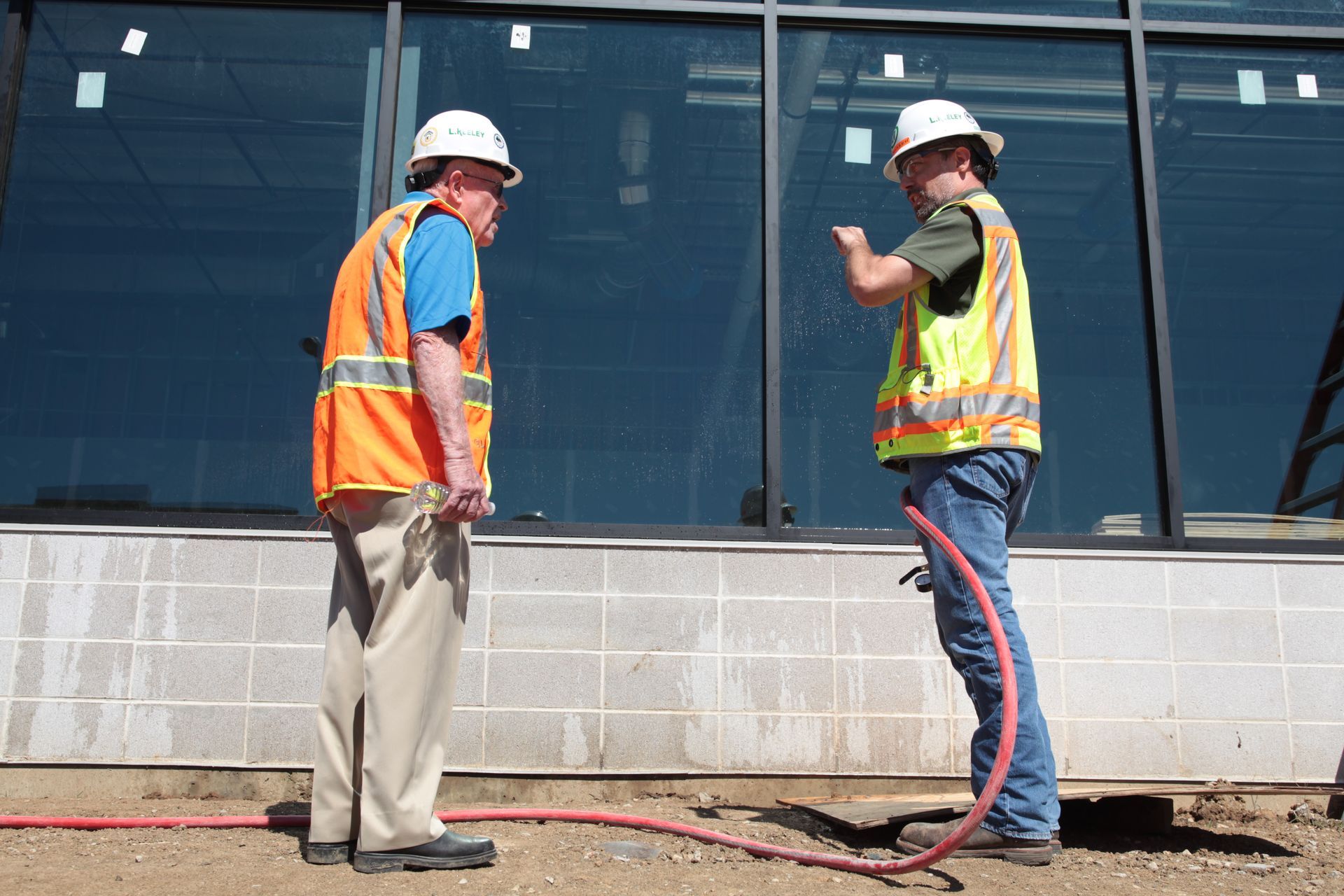 Two construction workers are standing in front of a building under construction