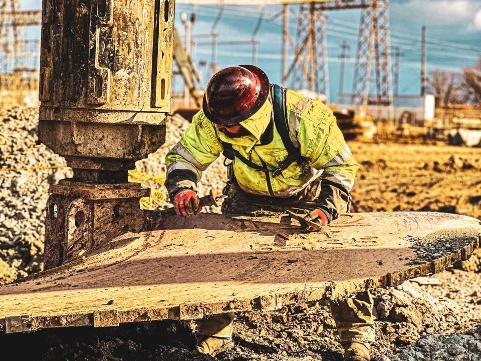 A construction worker is working on a piece of wood on a construction site.