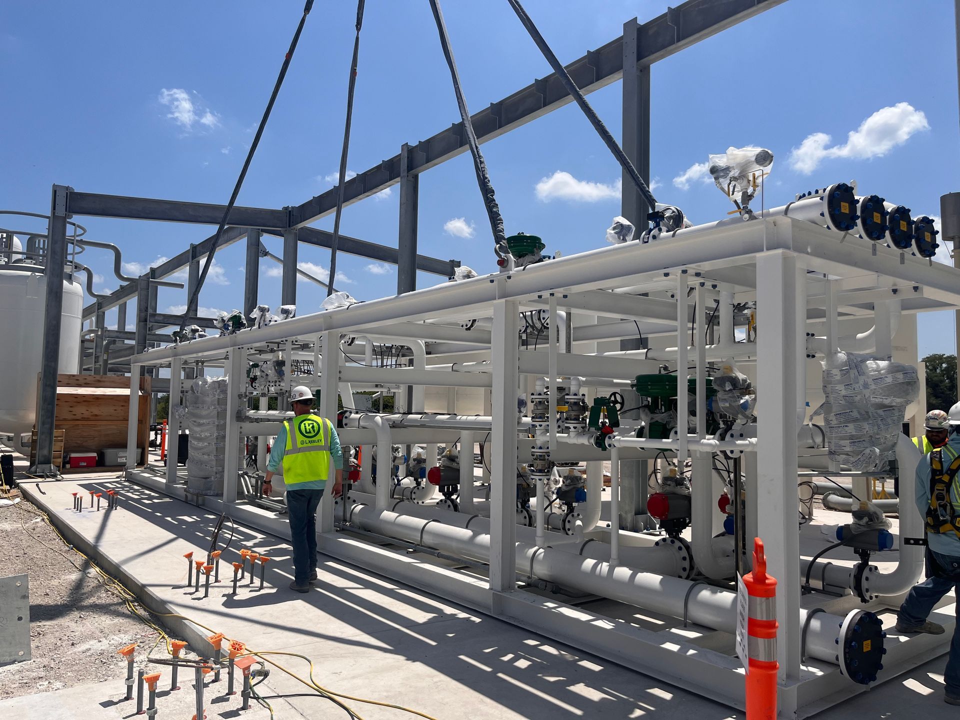 A man in a yellow vest is standing in front of a large metal structure.