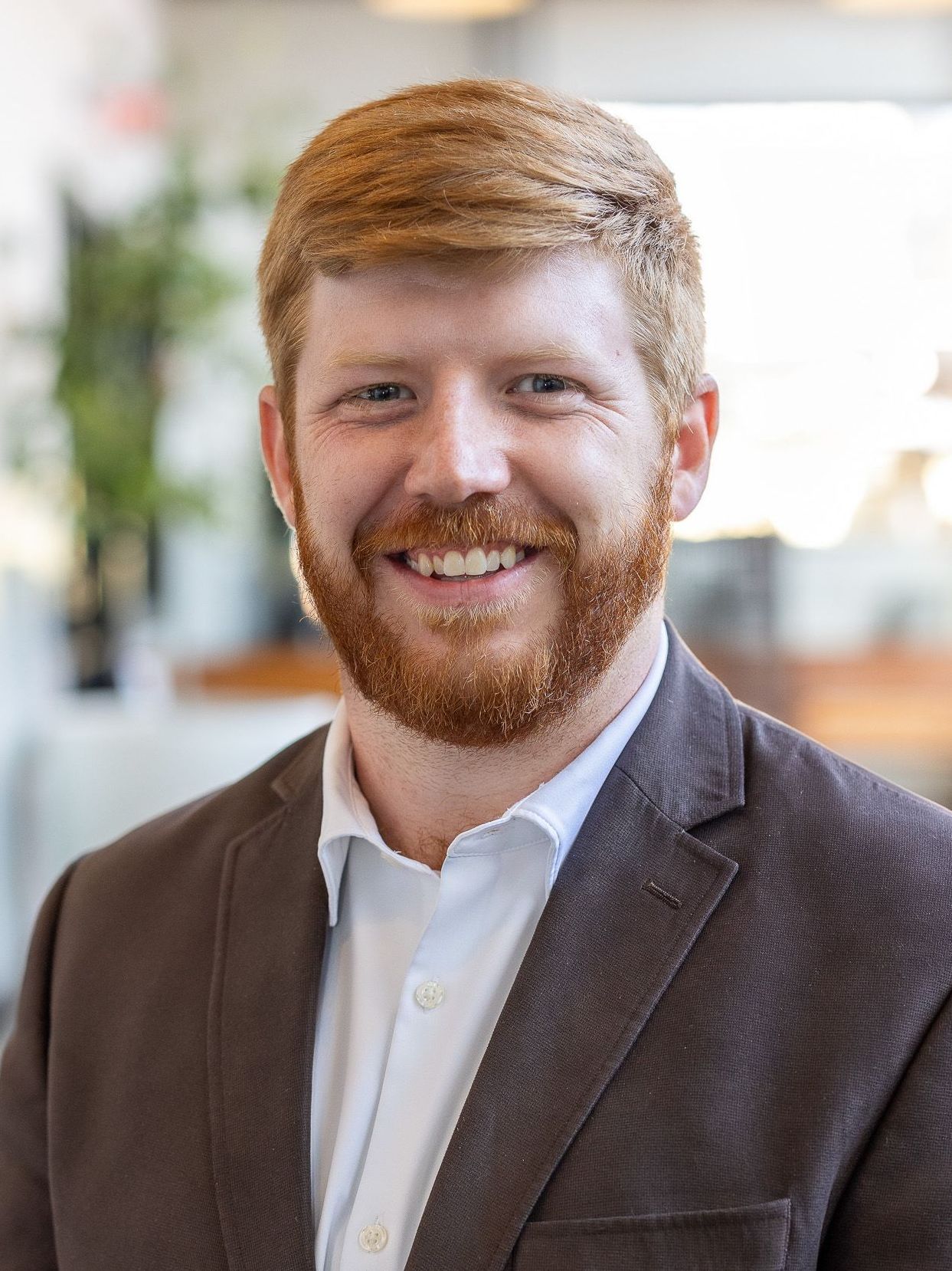 A man with a beard is wearing a suit and smiling for the camera.