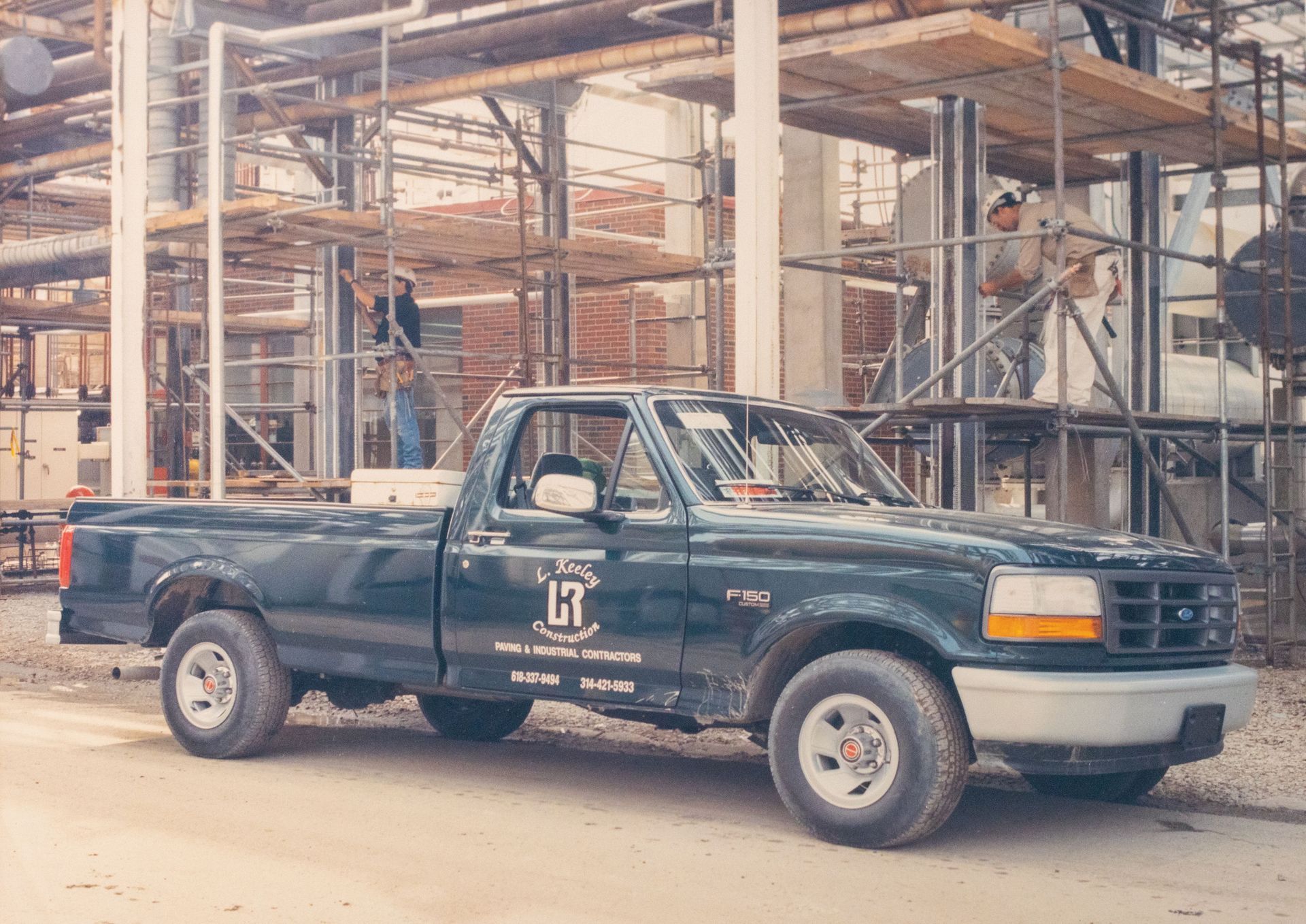 A ford truck is parked in front of a building under construction