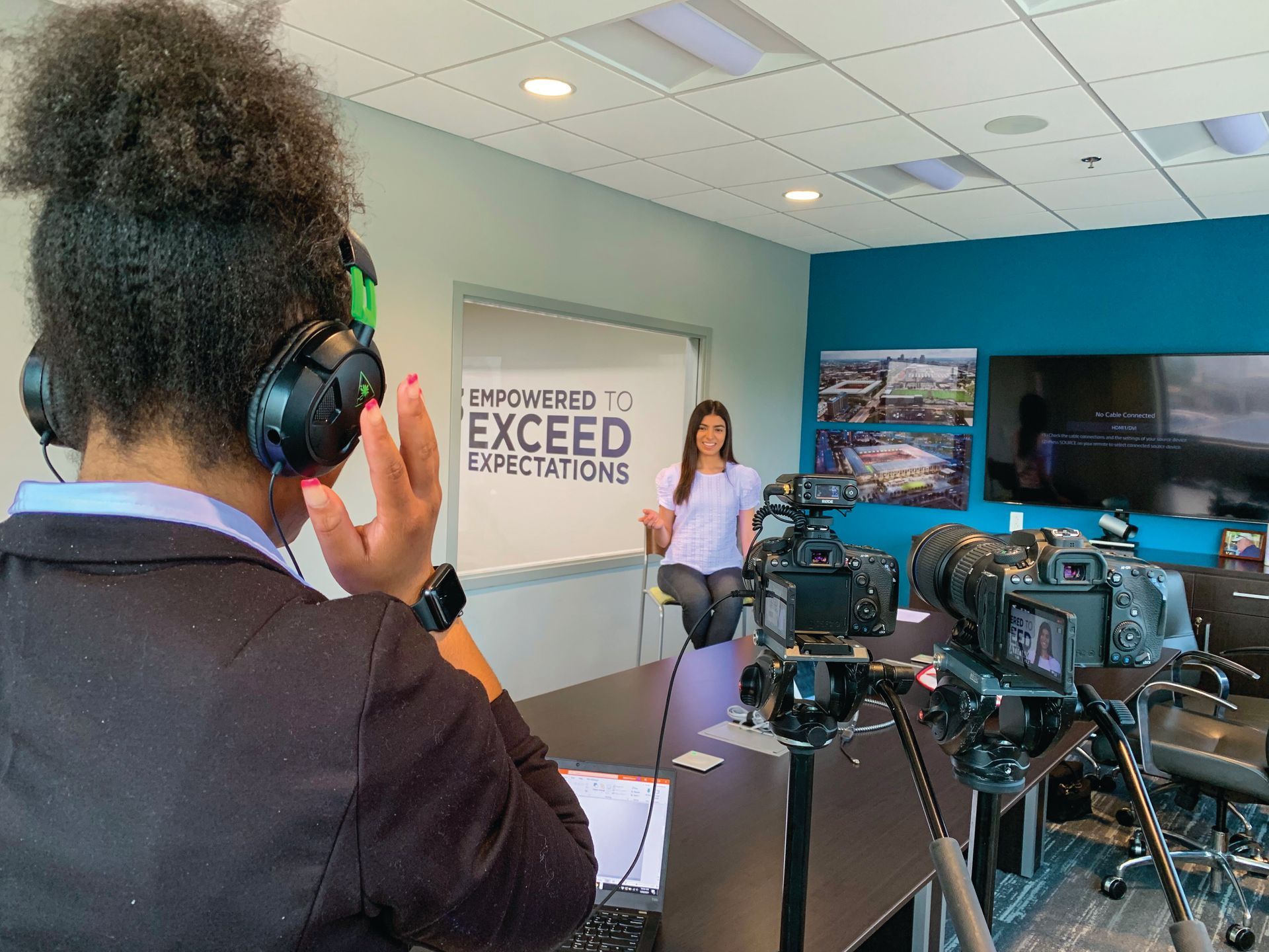 A woman wearing headphones is recording a woman sitting at a table.