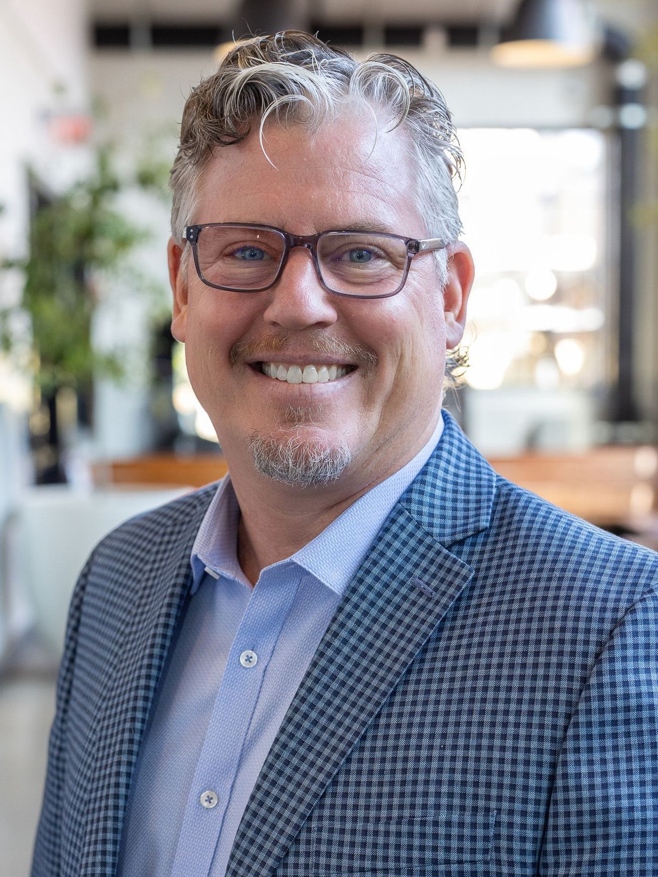 A man wearing glasses and a suit is smiling for the camera.