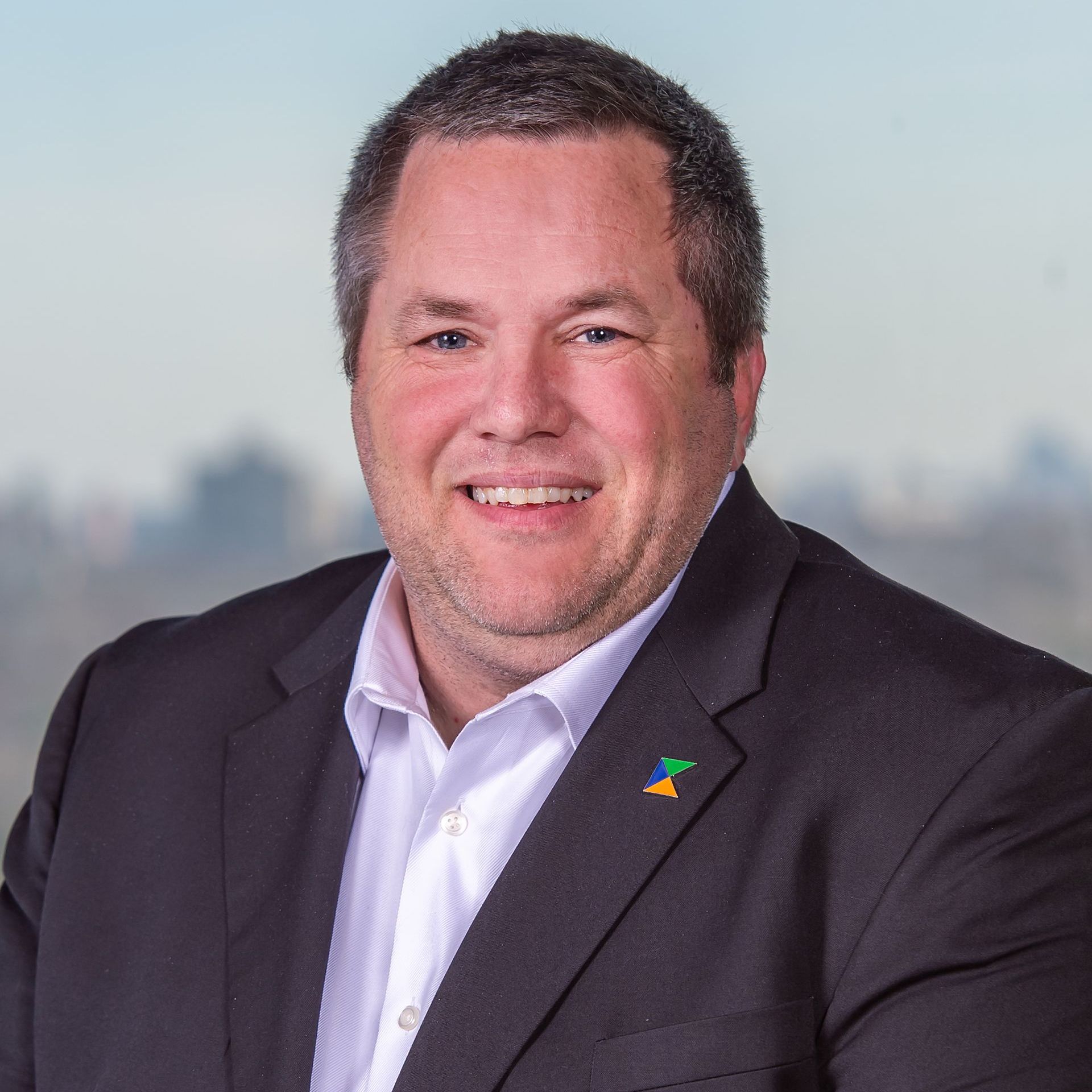 A man in a suit and white shirt is smiling for the camera.