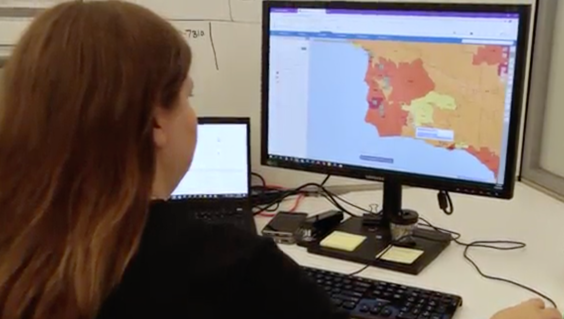 A woman is looking at a map on a computer screen.