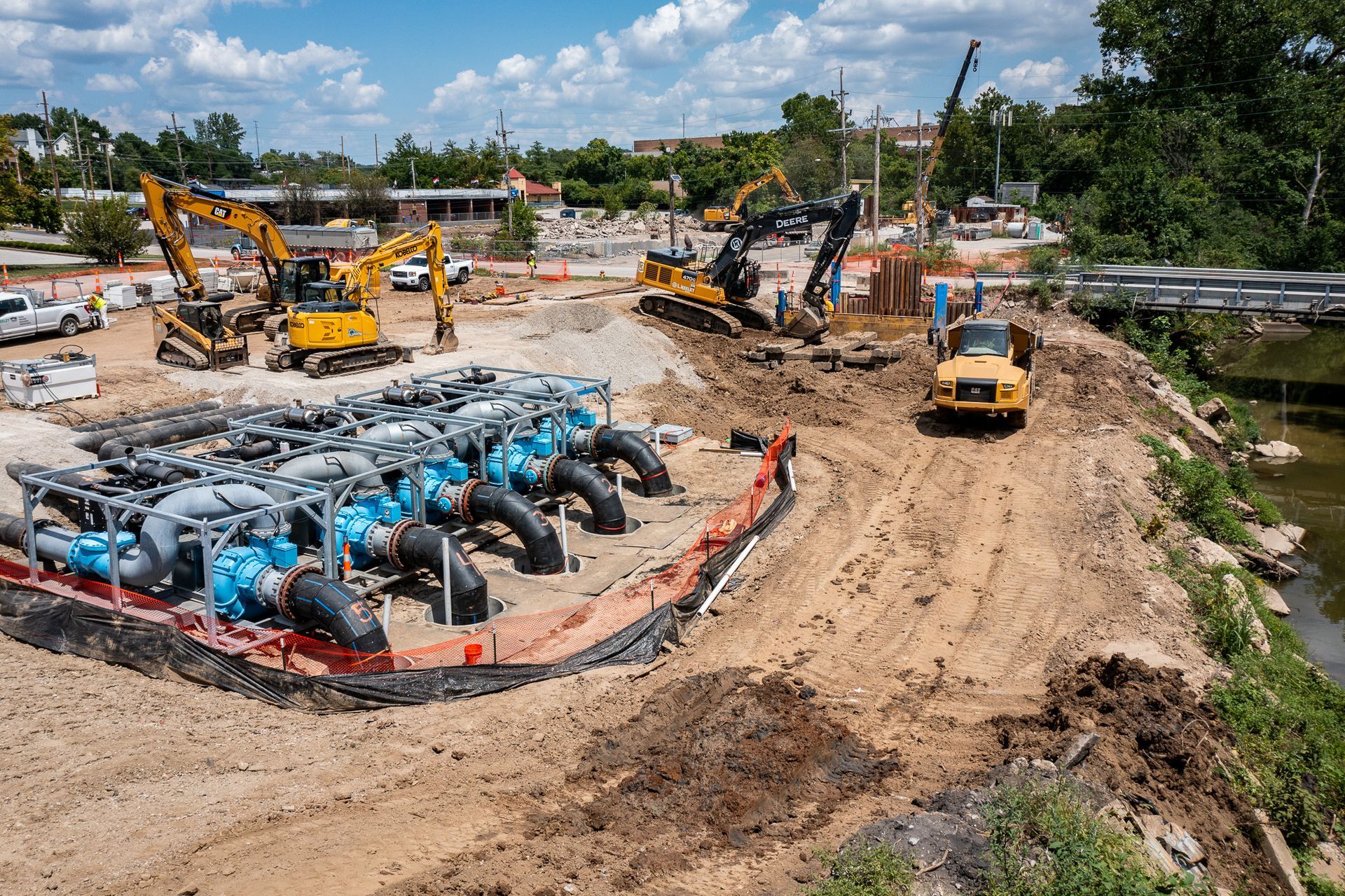 A construction site with a lot of machinery and pipes in the dirt.