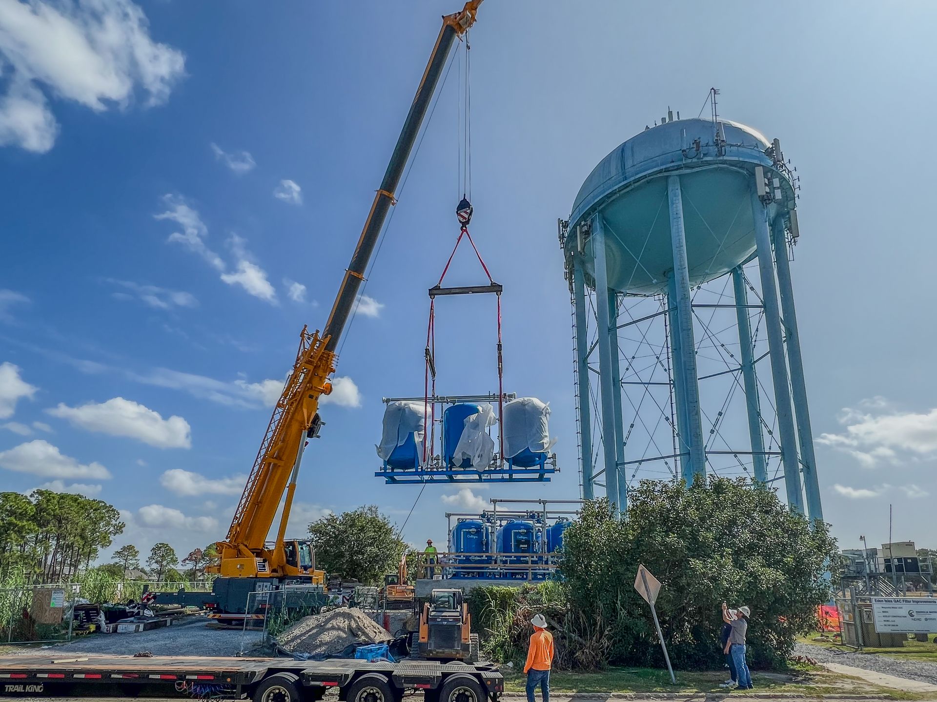 A crane is lifting a water tower into the air.