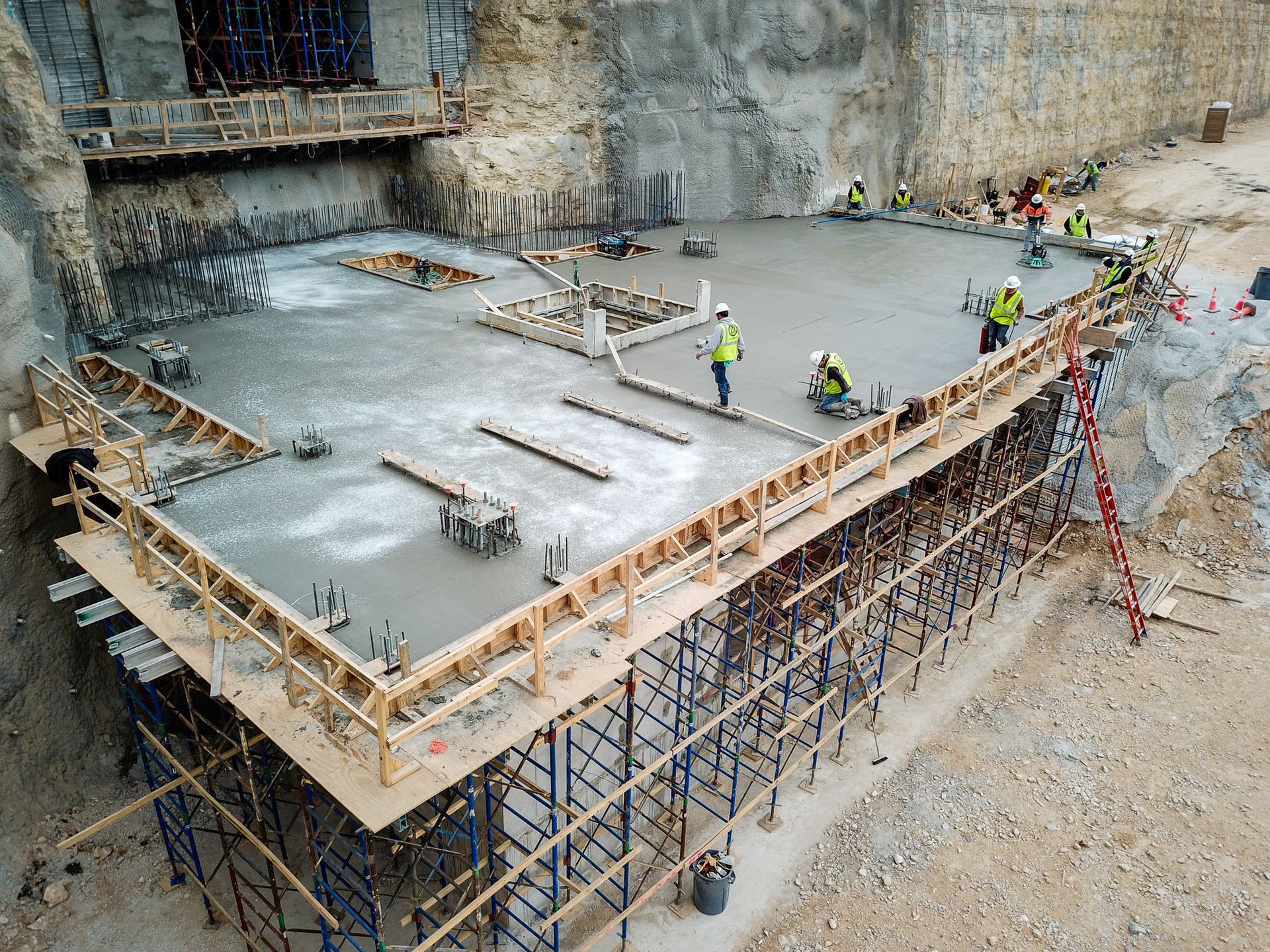 A group of construction workers are working on a concrete floor.