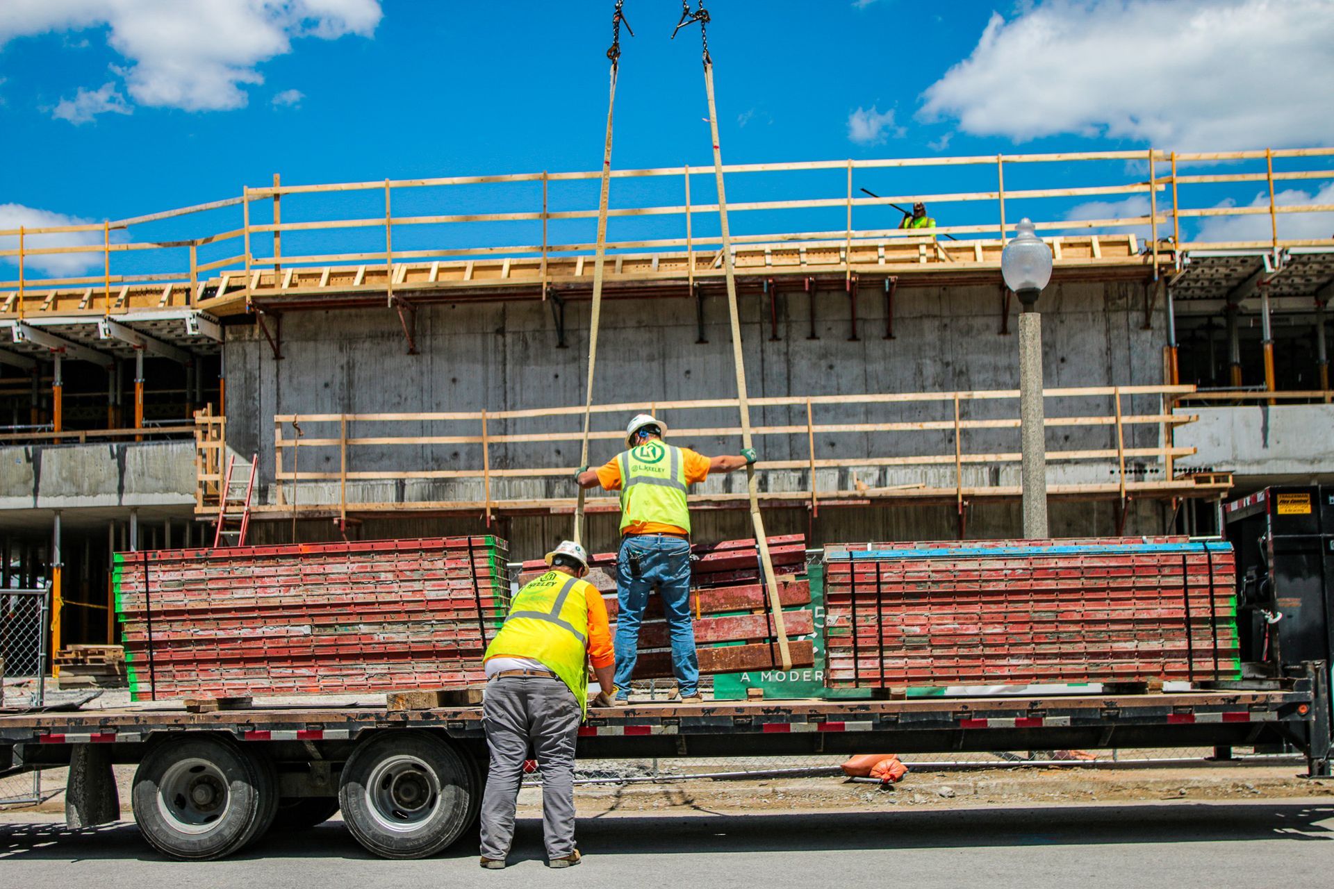 Two construction workers are working on a trailer at a construction site.