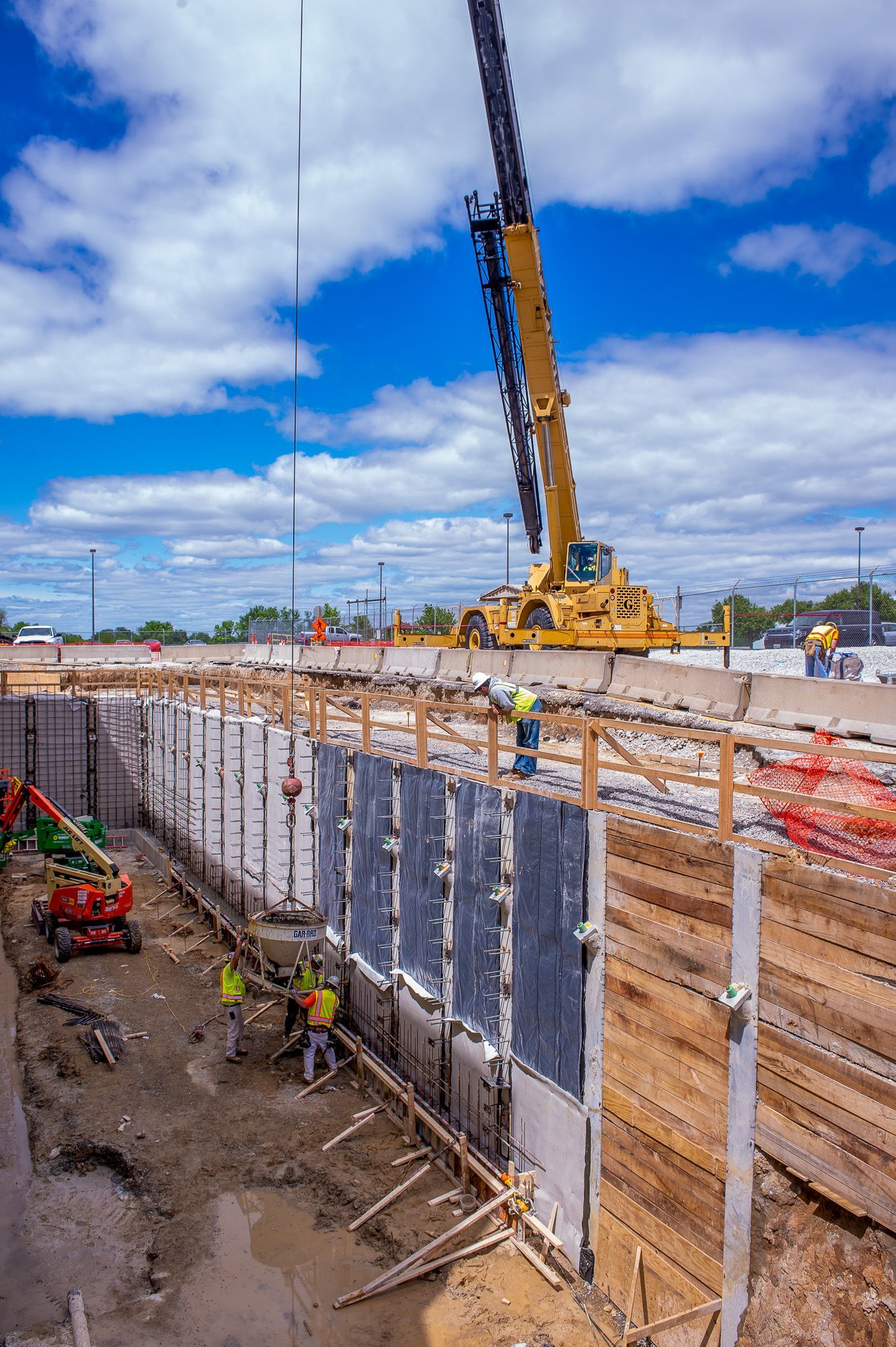 A construction site with a crane lifting a concrete wall.