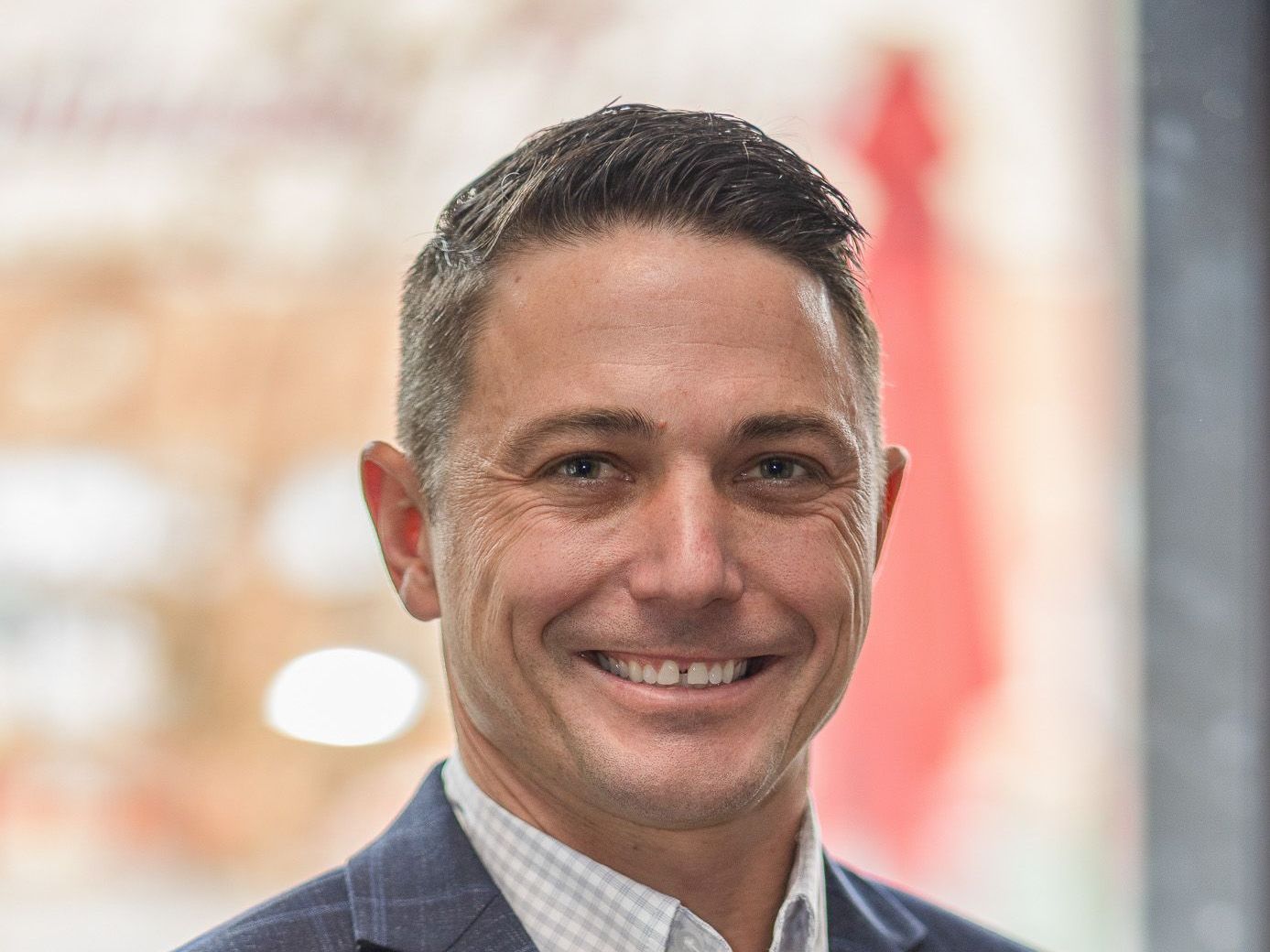 A man in a suit and plaid shirt is smiling for the camera.