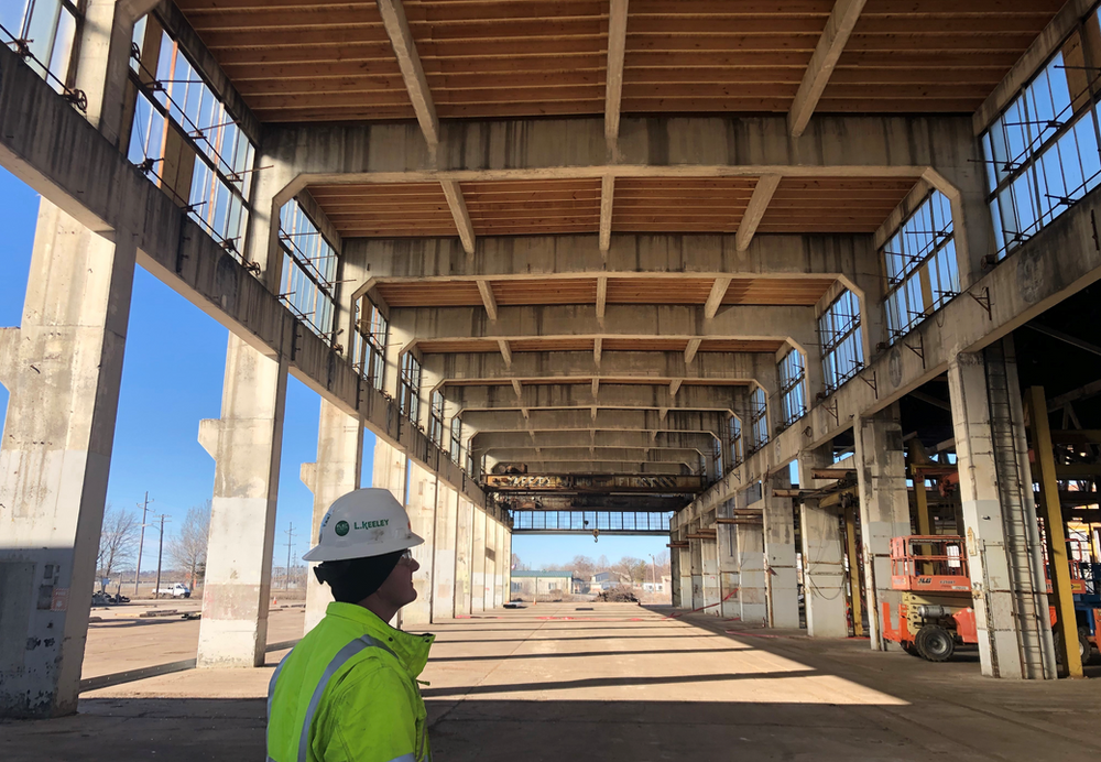 A man in a hard hat is standing in an empty building.