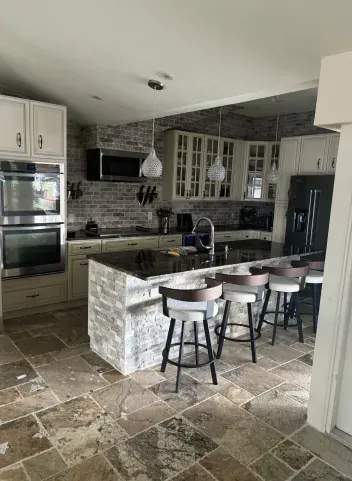 A kitchen with a large island and stools in it.