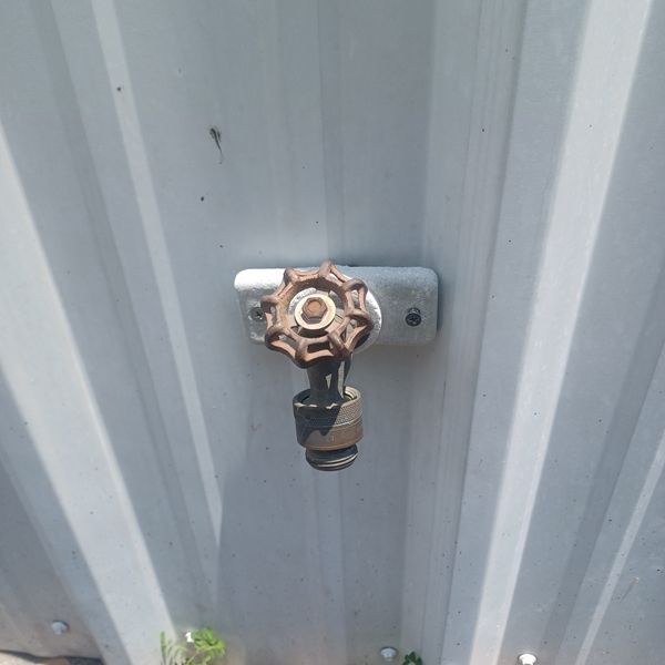 A close up of a faucet on a white wall