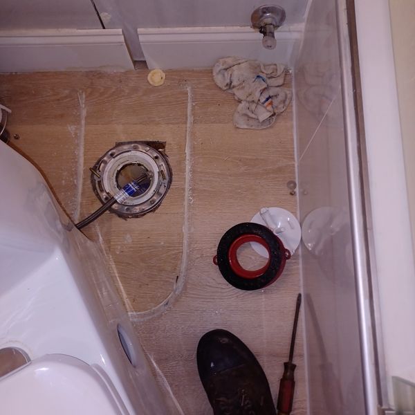 A bathroom with a toilet and a screwdriver on the floor