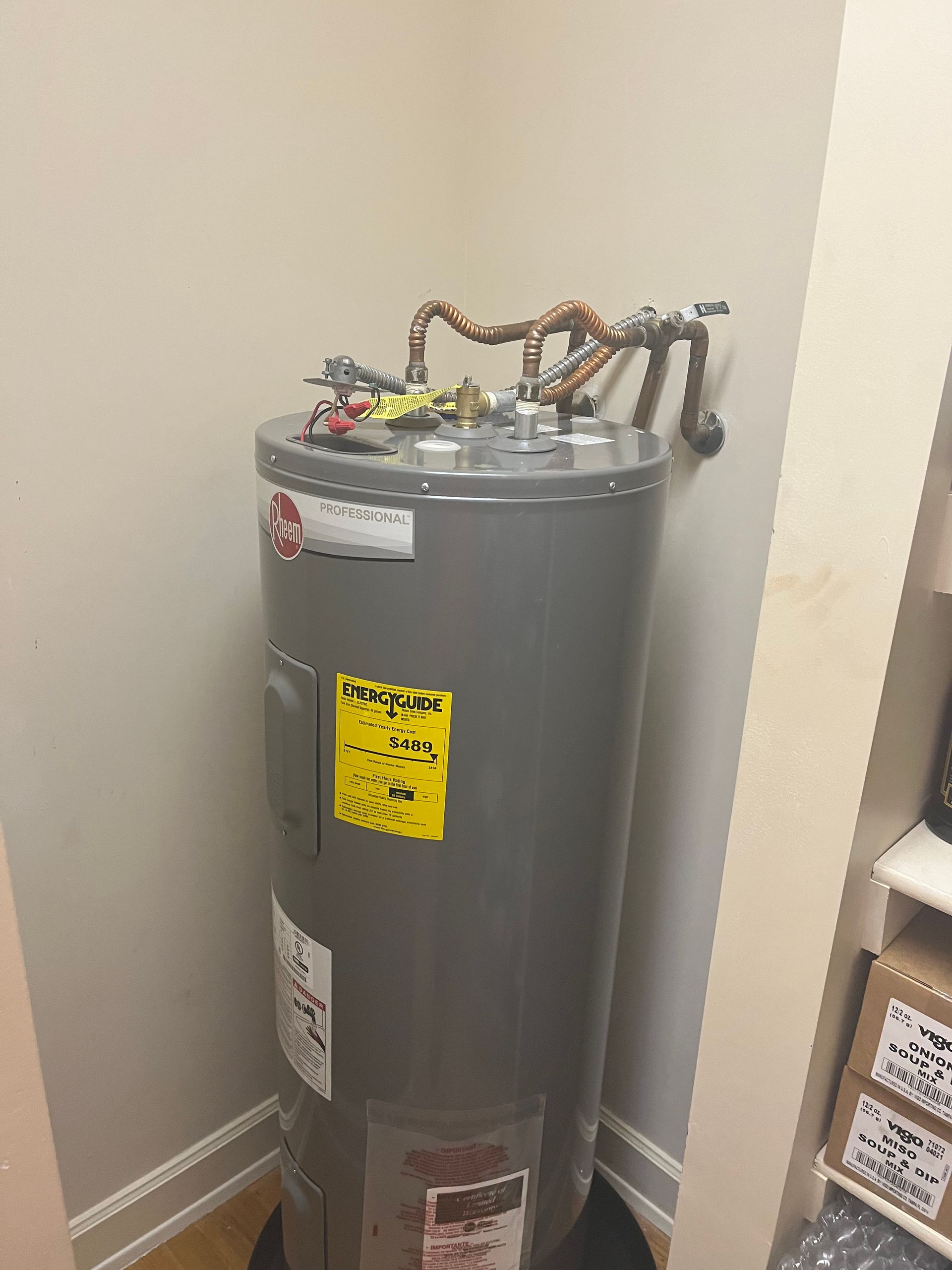A water heater is sitting in a corner of a room.