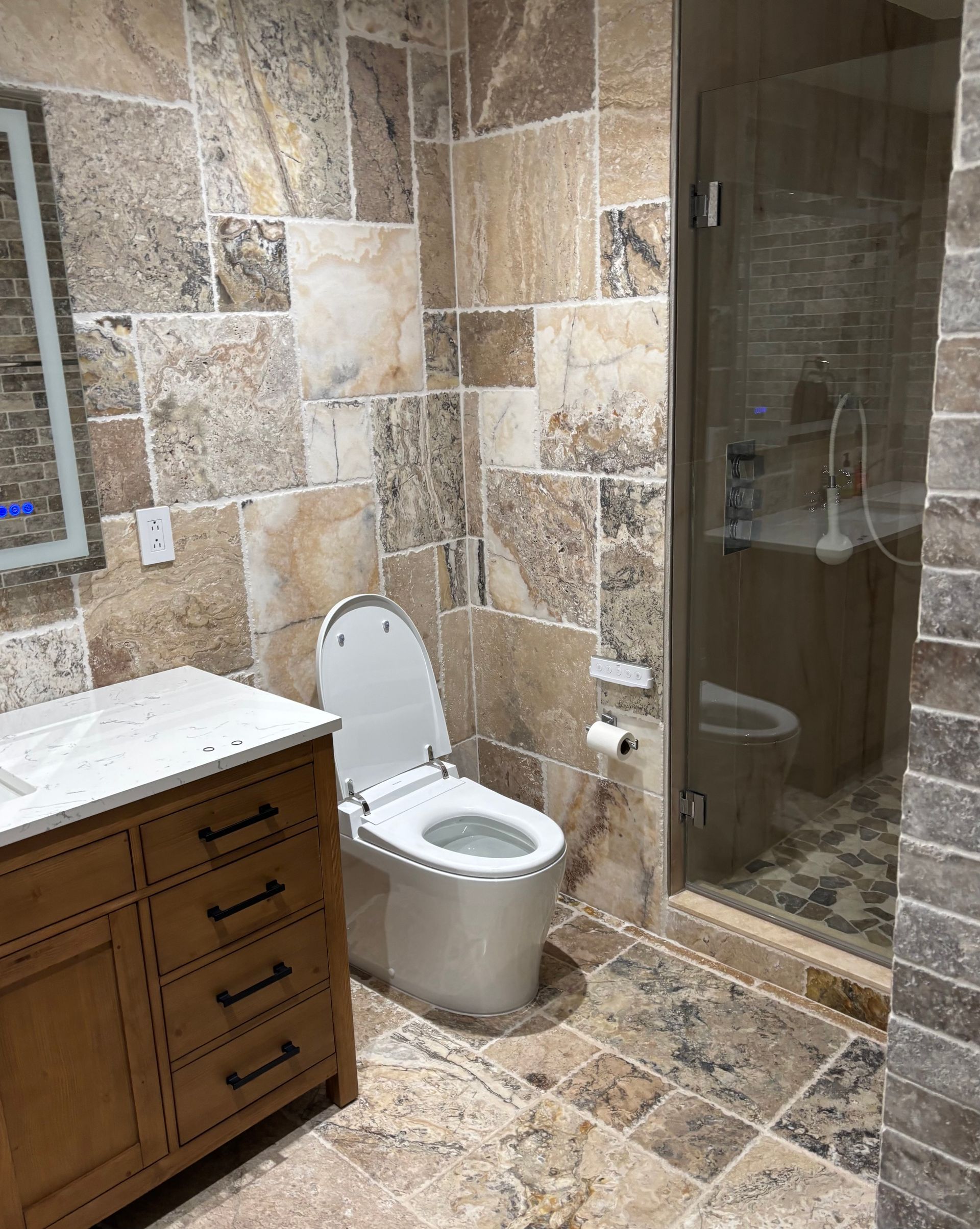A bathroom with a toilet , sink and shower.