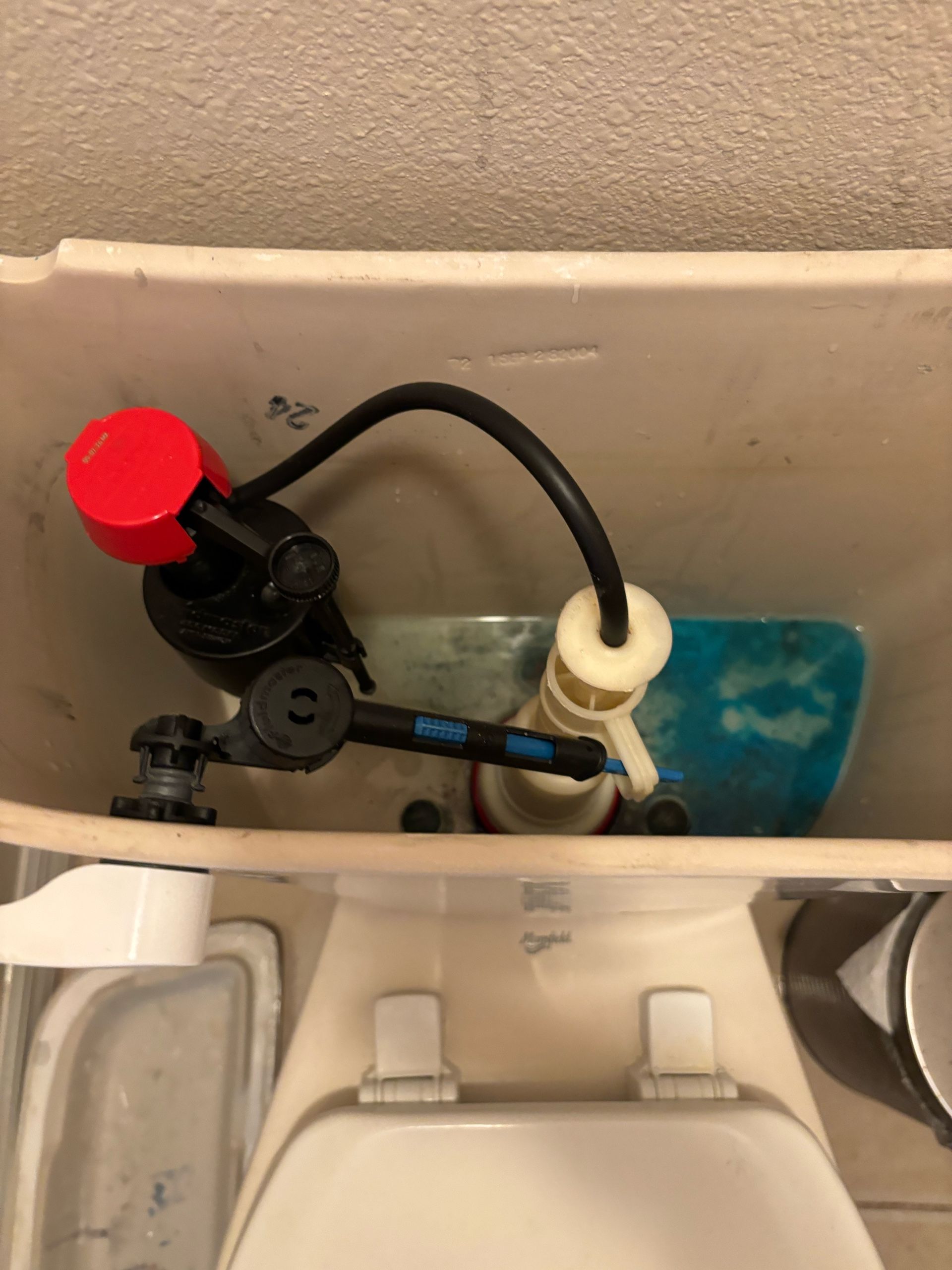 A toilet with a red top and a black hose attached to it