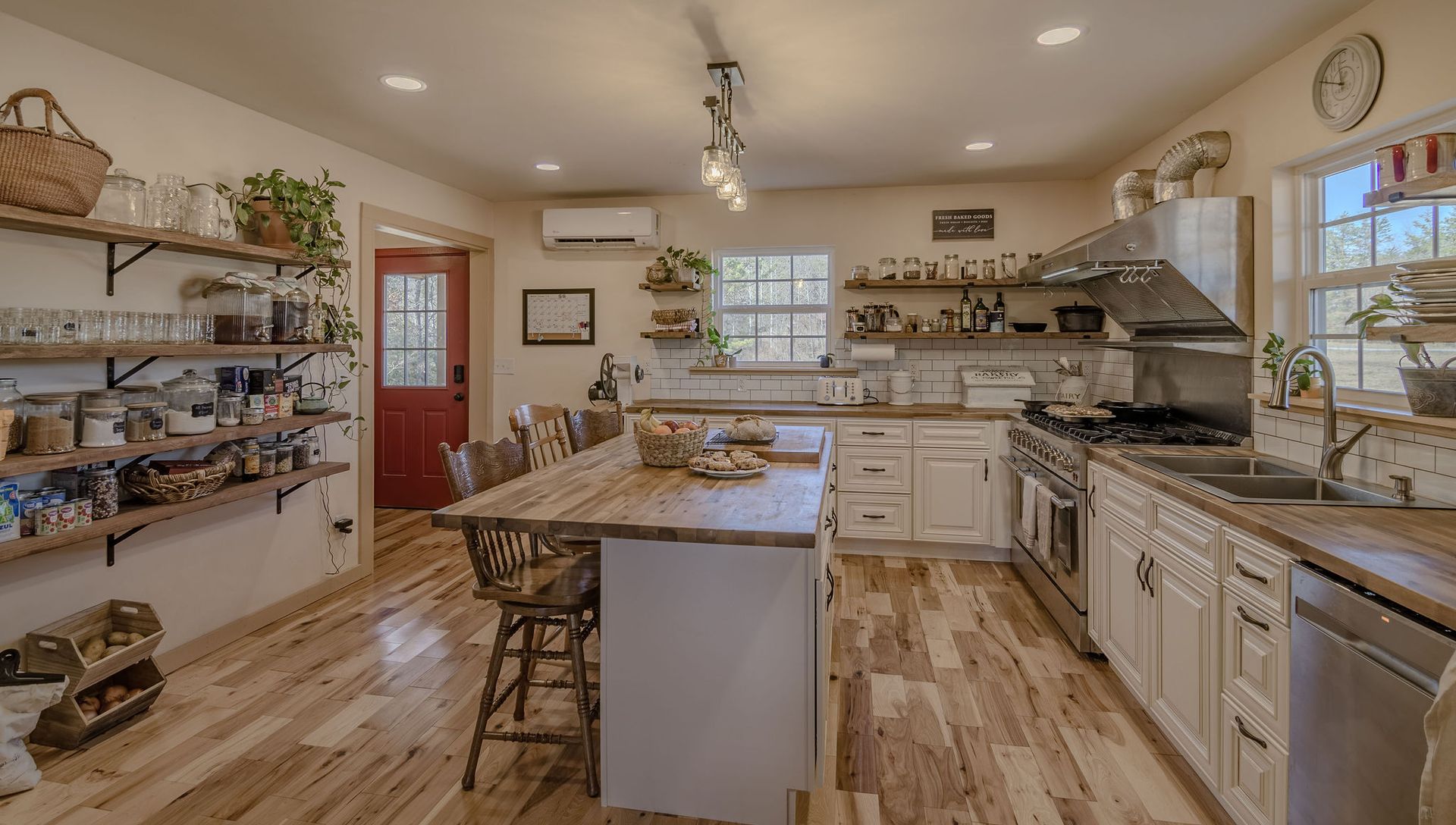 Rustic kitchen with a wooden island, white cabinetry, open shelving, and light-colored wood flooring.