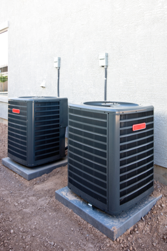 Two air conditioners are sitting outside of a building.