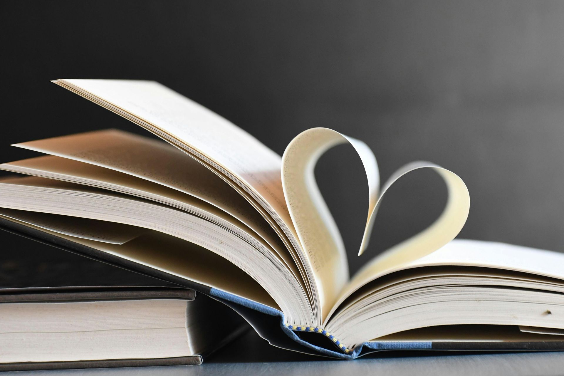 Open book with pages folded into a heart shape on a dark surface