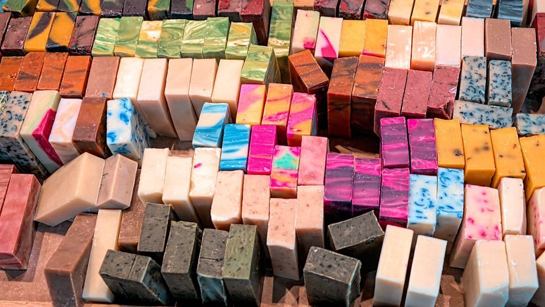 Assorted colorful handmade soap bars displayed on a surface. The soaps vary in color and pattern.