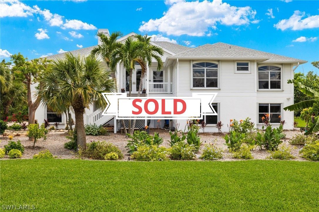 A large white house with a sold sign in front of it.