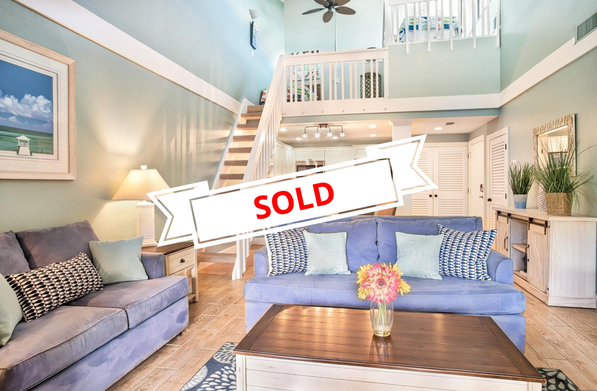 A living room with a blue couch and a sold sign