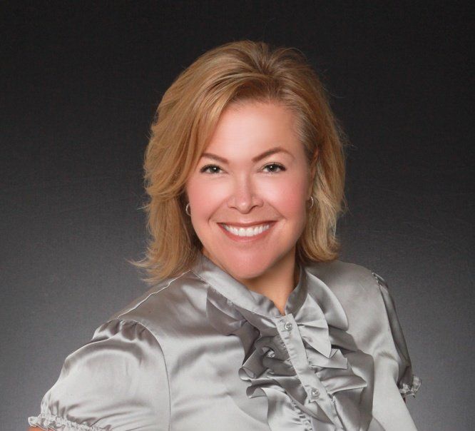 A woman in a satin blouse is smiling for the camera