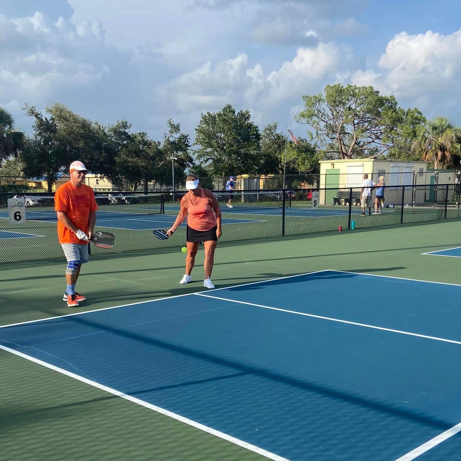 A man and a woman are playing tennis on a tennis court.