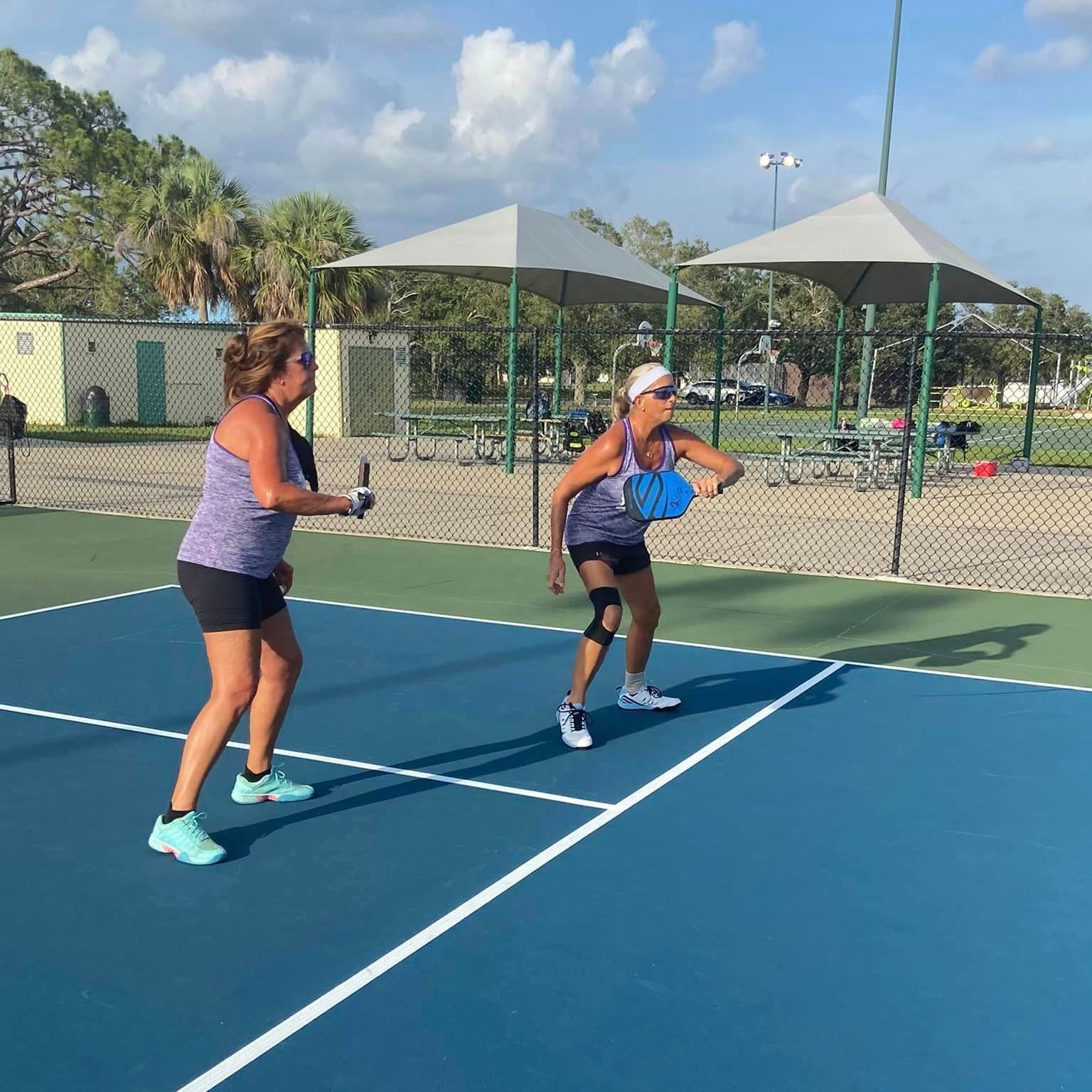 Two women are playing tennis on a blue court