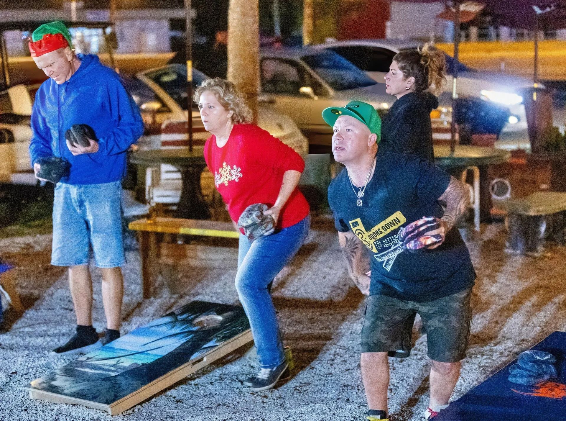 A group of people are playing a game of cornhole in a parking lot.