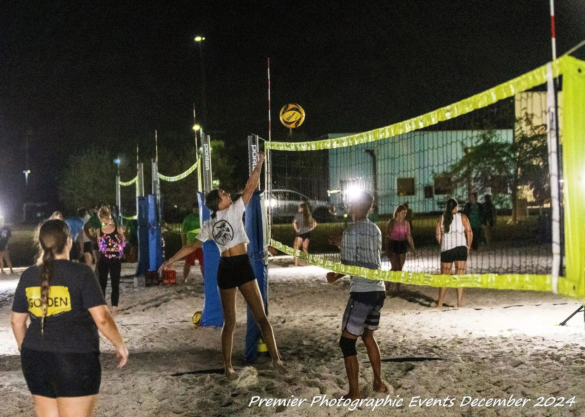 A group of people are playing volleyball on a beach at night