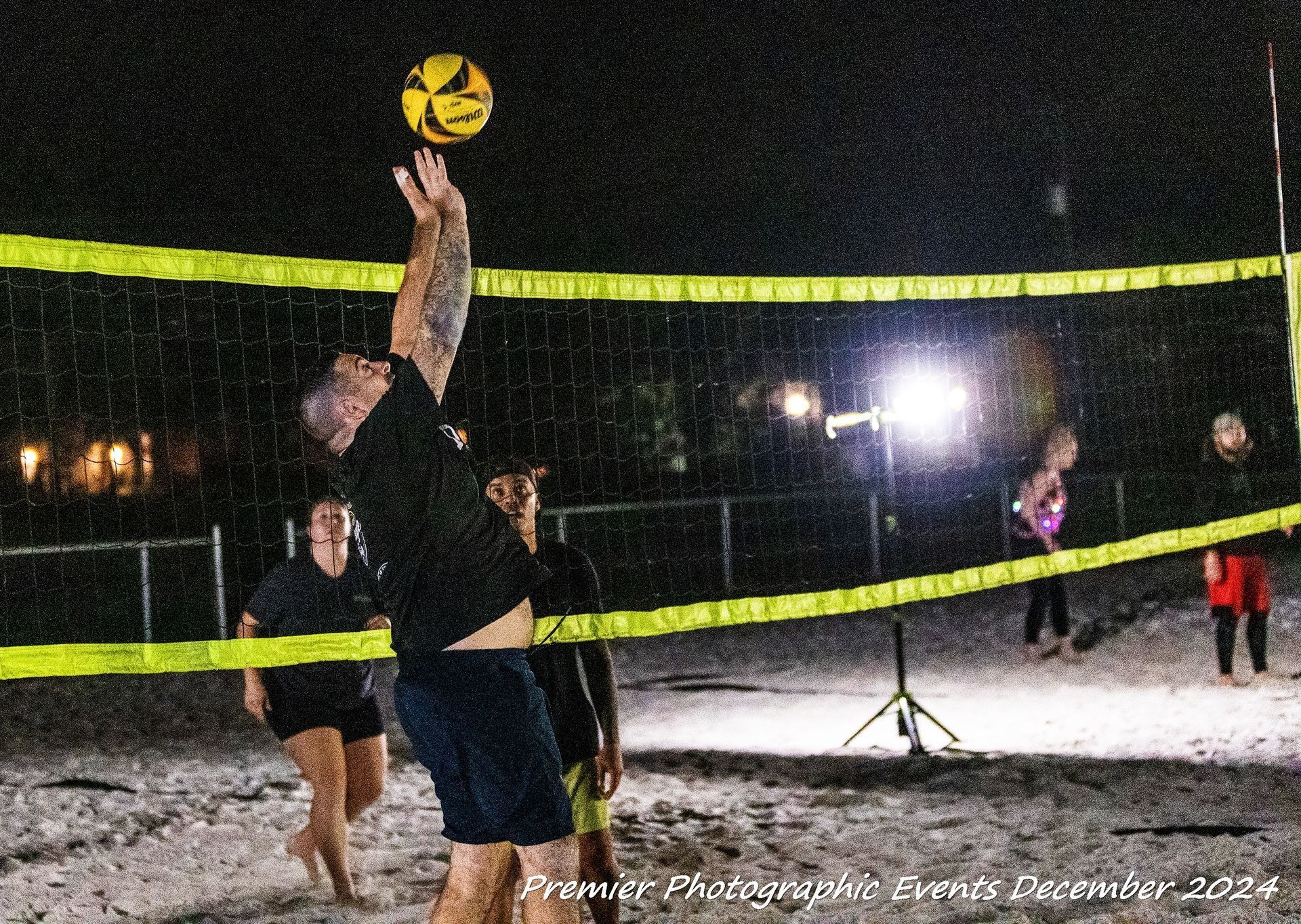 A group of people are playing volleyball on a beach at night