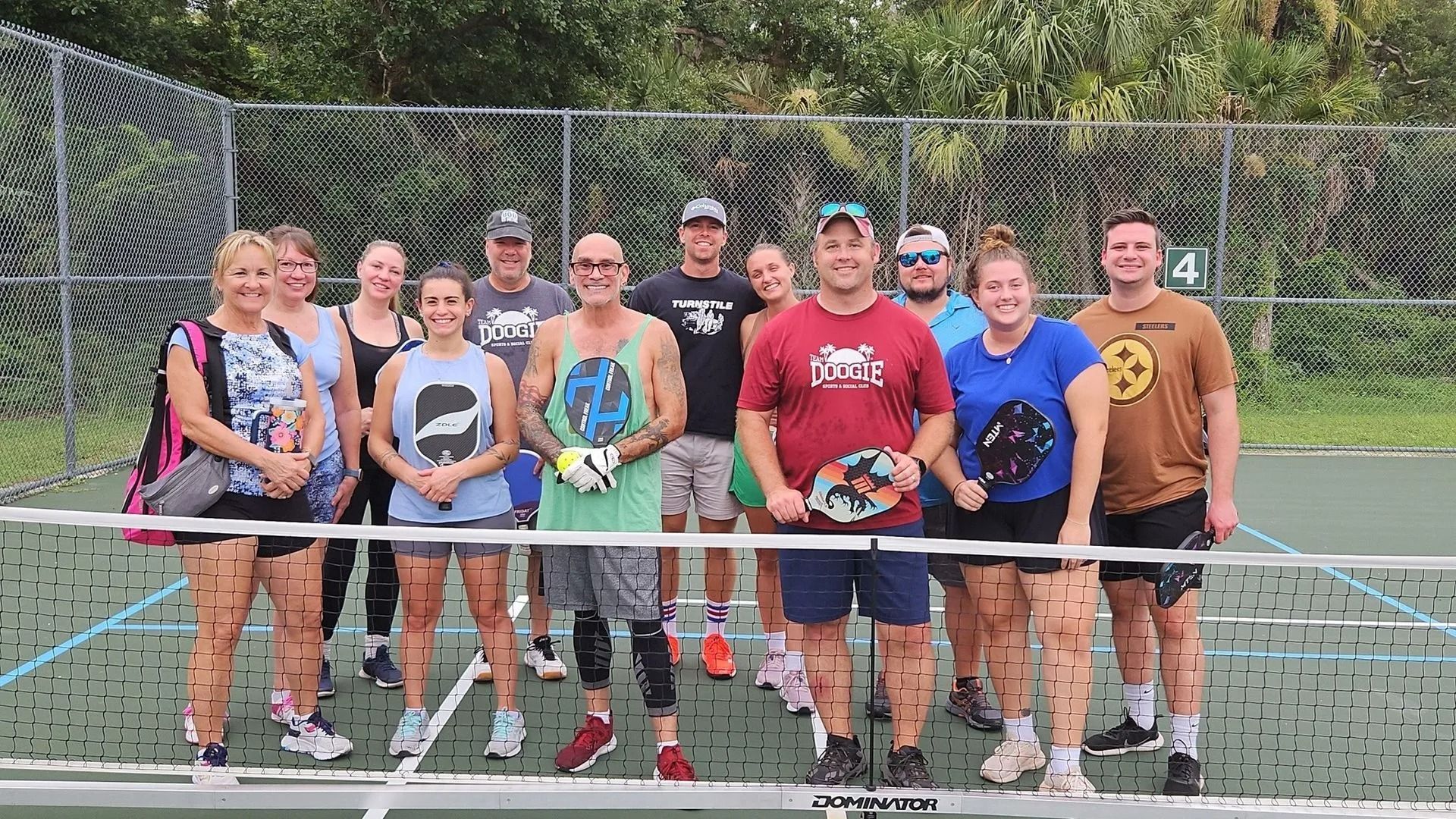 A group of people are posing for a picture on a tennis court.