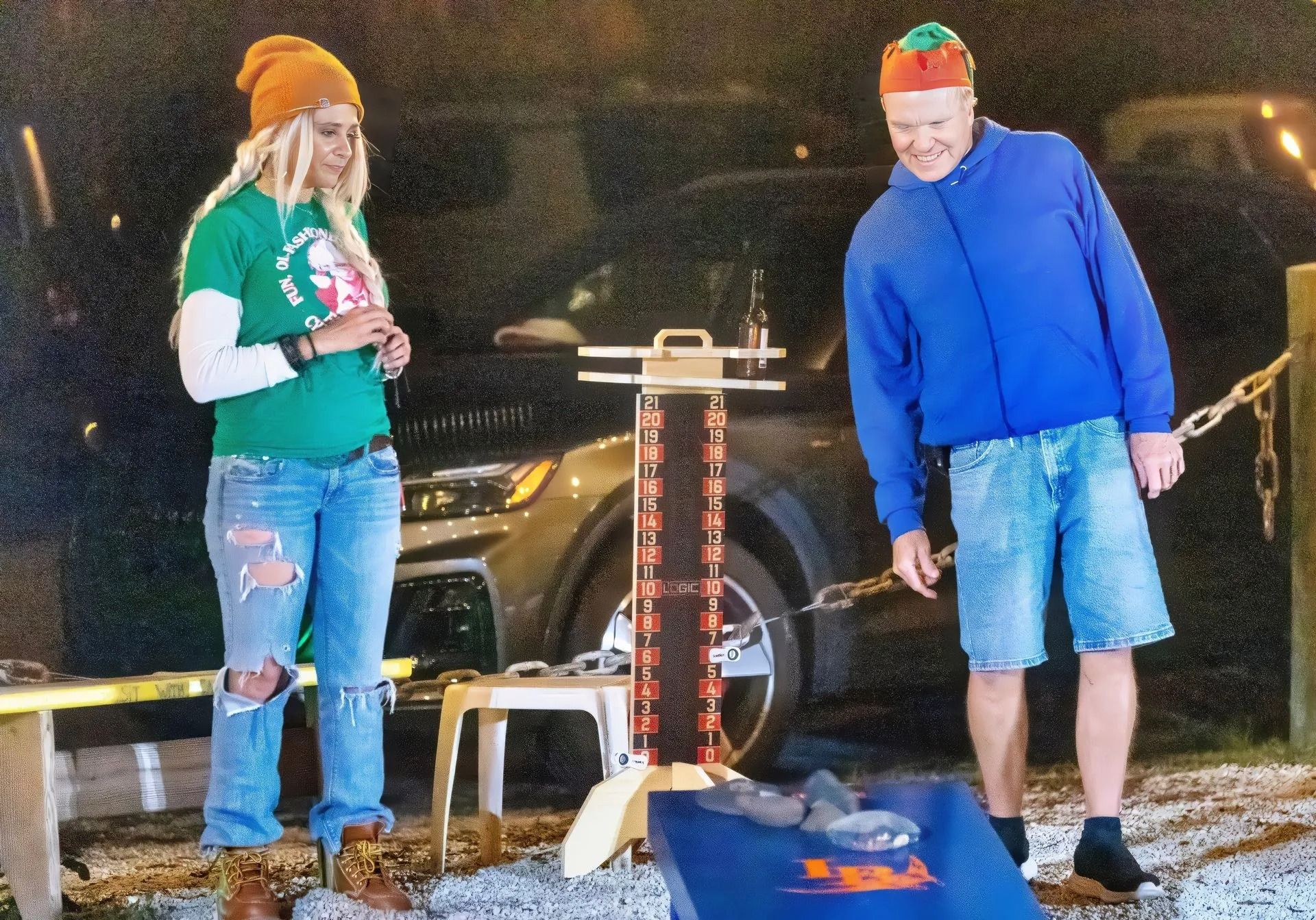 A man and a woman are playing a game in front of a car