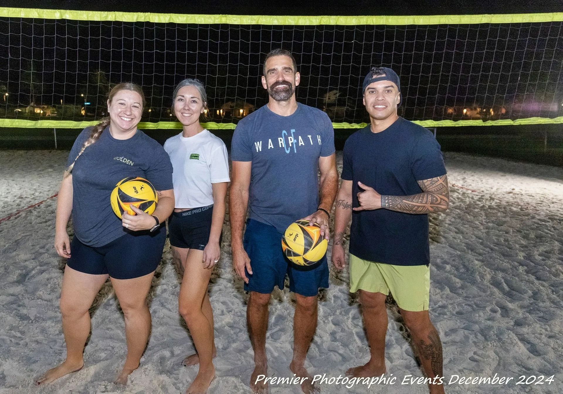 A group of people standing on a beach holding volleyballs.